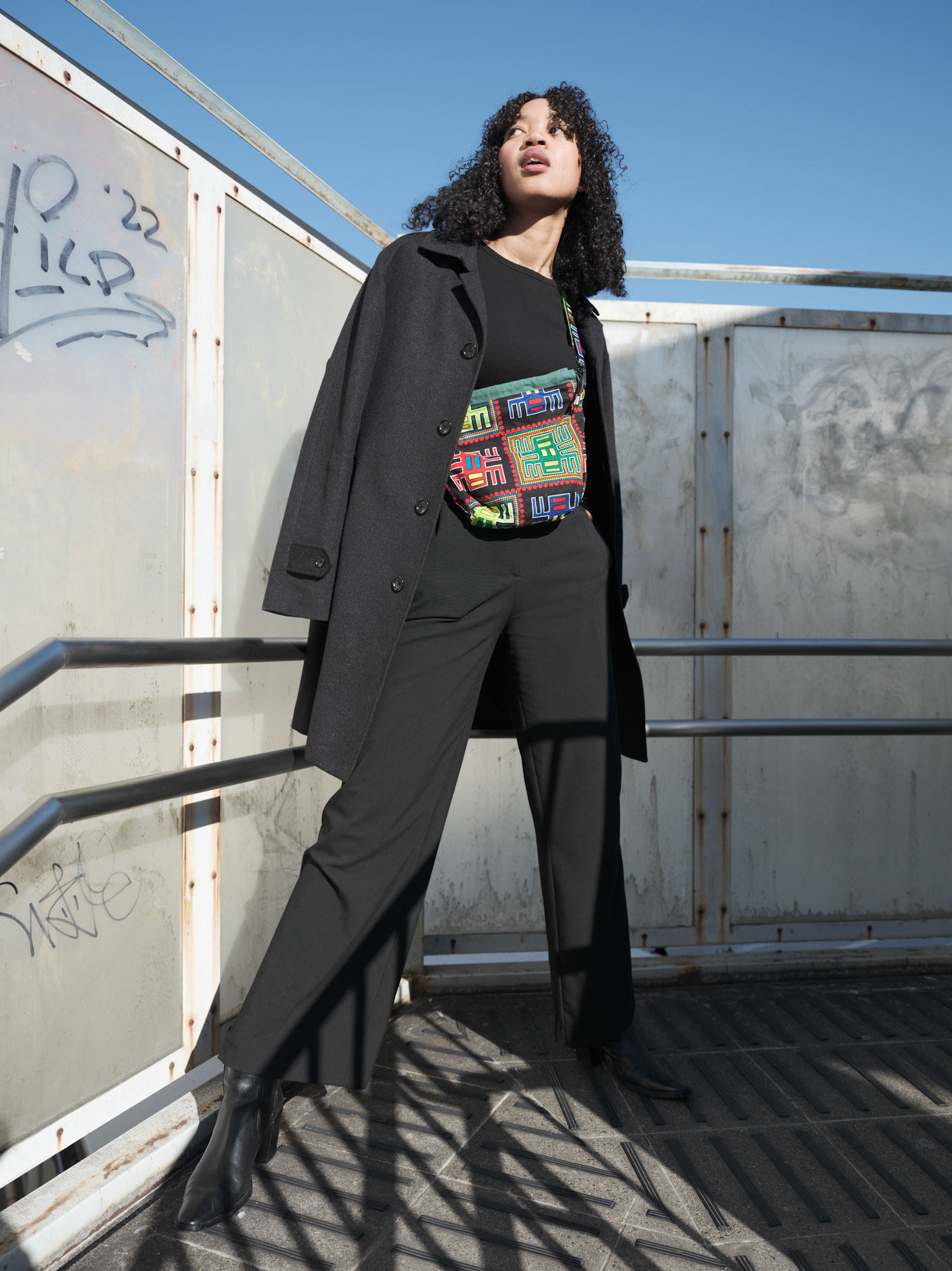 Ikeji Uju:  Emily Osas, a stunning mixed Japanese model elegantly adorned in a black crop top, black long pants, and black long coat set against the backdrop of Nakameguro City, Tokyo, Japan. Ikeji Uju Photography