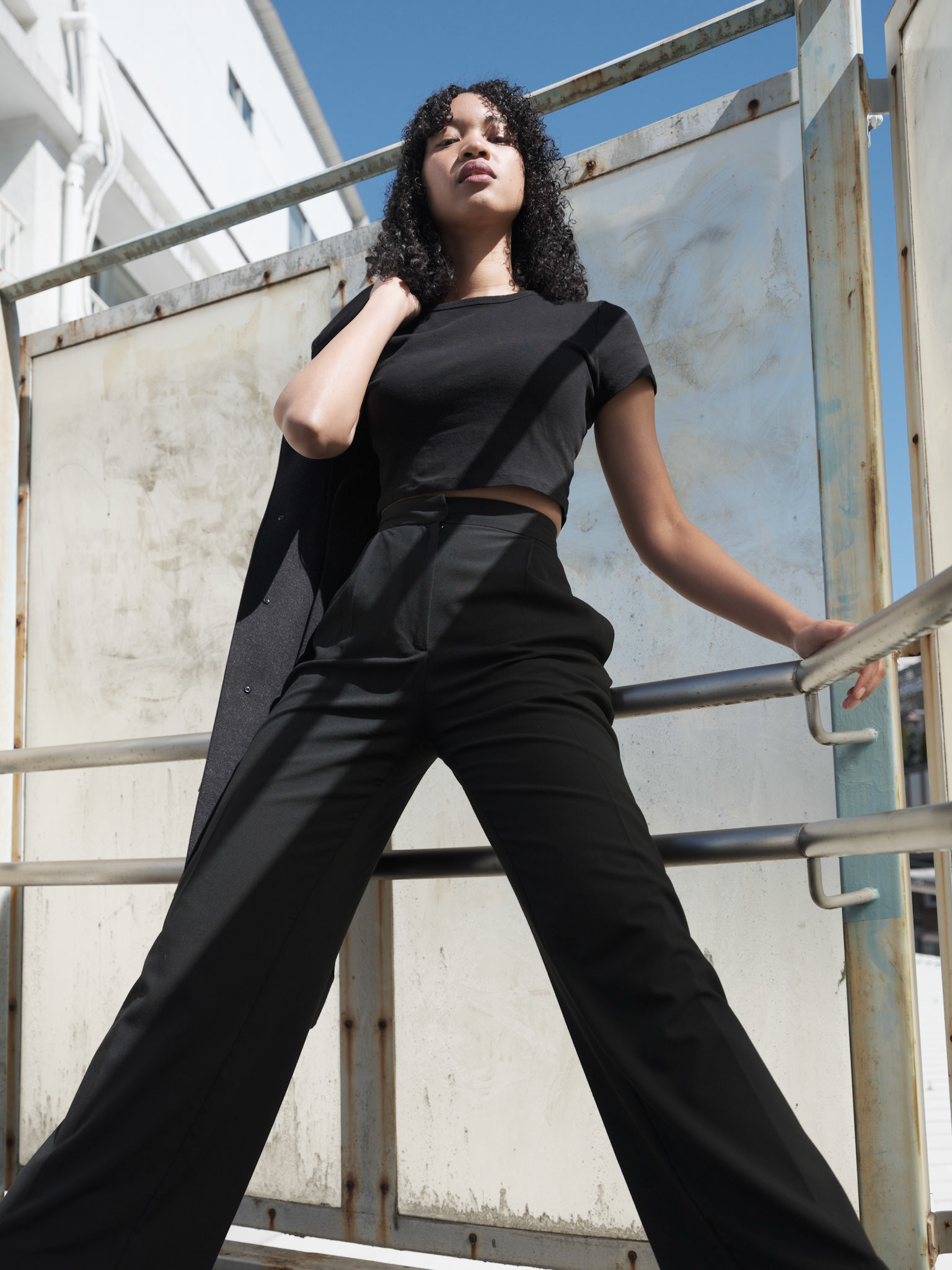 Ikeji Uju:  Emily Osas, a stunning mixed Japanese model elegantly adorned in a black crop top, black long pants, and black long coat set against the backdrop of Nakameguro City, Tokyo, Japan. Ikeji Uju Photography