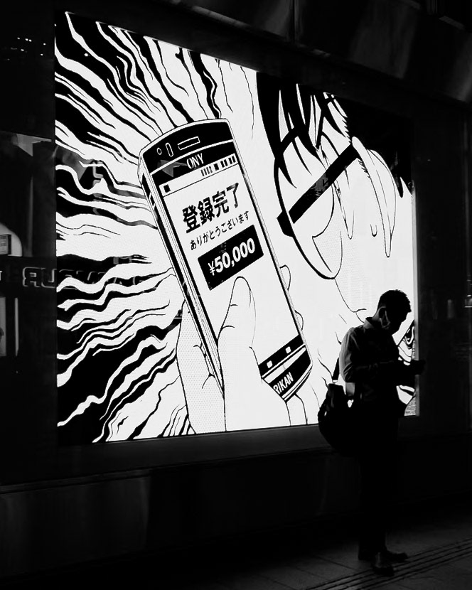 Captured by Ikeji Uju: A silhouette of a man standing in front of a billboard in Tokyo, Japan.