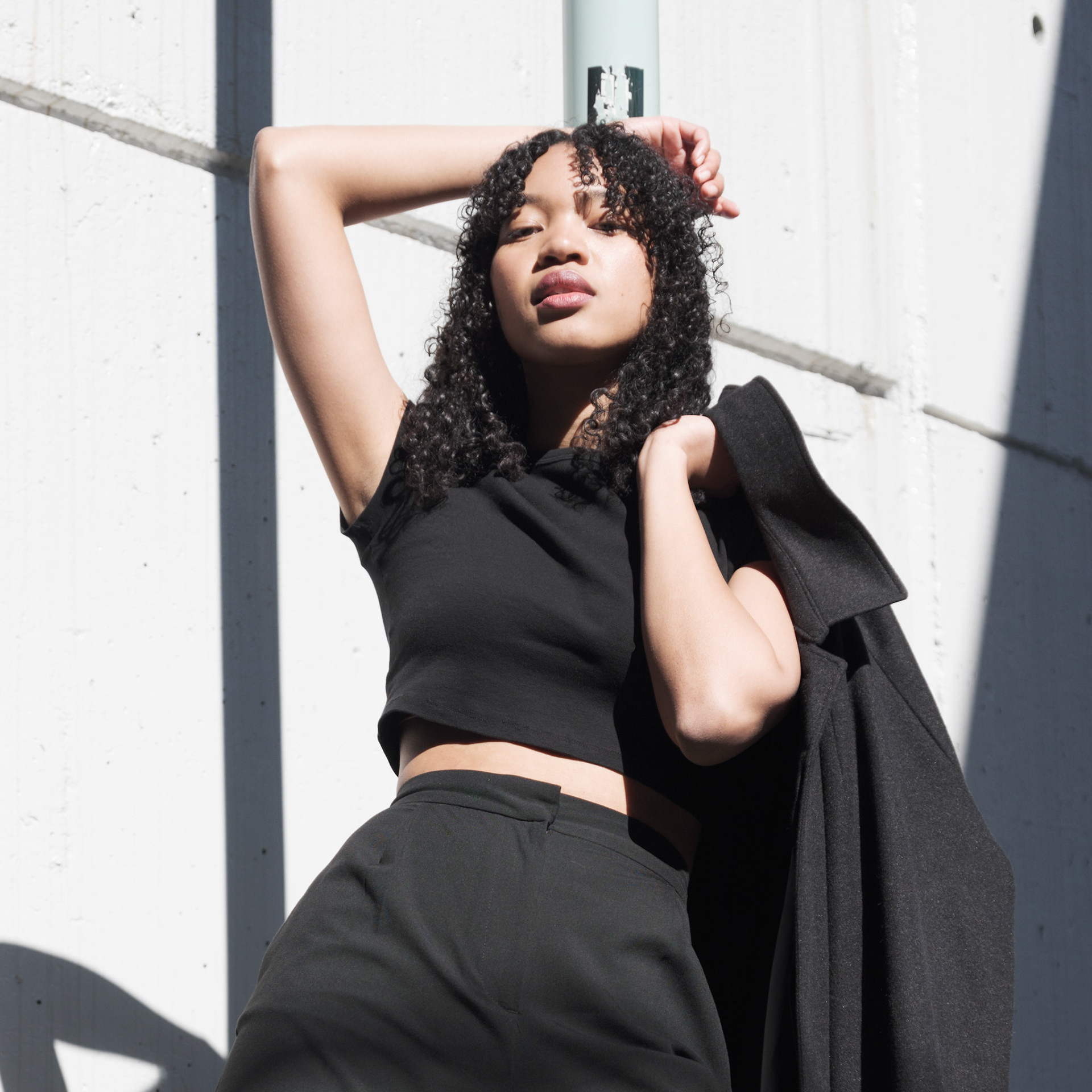 Ikeji Uju:  Emily Osas, a stunning mixed Japanese model elegantly adorned in a black crop top, black long pants, and black long coat set against the backdrop of Nakameguro City, Tokyo, Japan. Ikeji Uju Photography