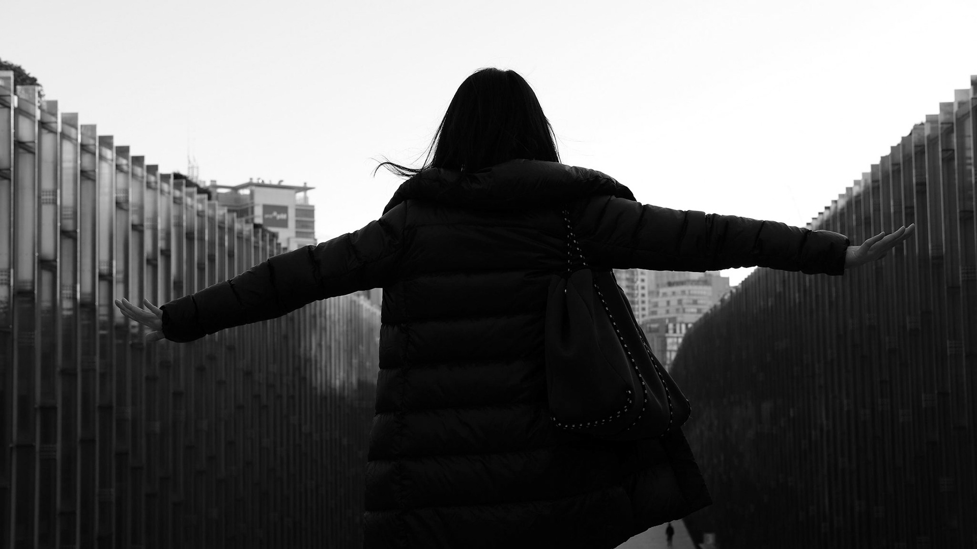 Captured by Ikeji Uju: A women standing with her arms spread out to her sides in Seoul, South Korea at Ewha Womans University during the daytime. Shot in Black and White.