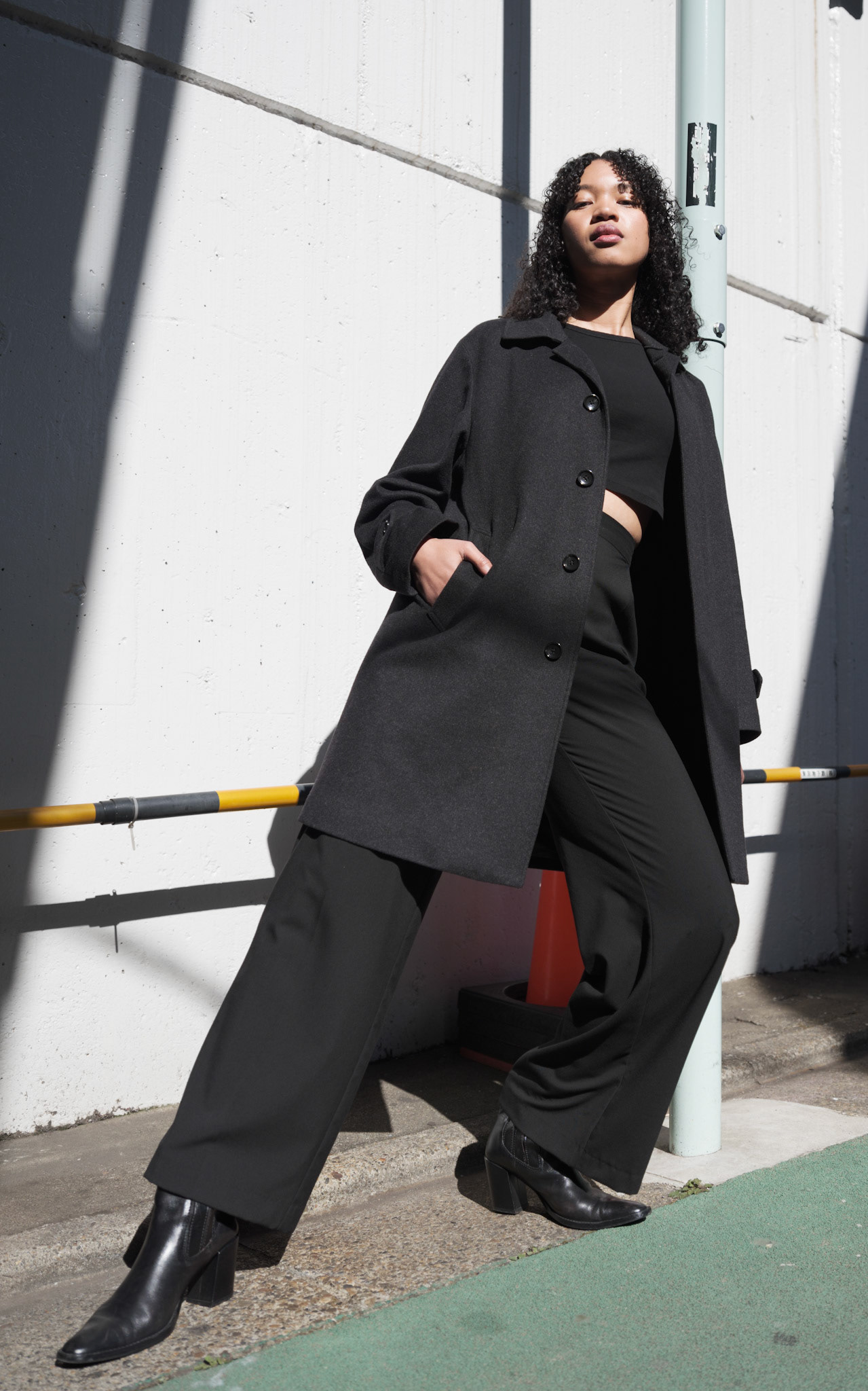 Ikeji Uju:  Emily Osas, a stunning mixed Japanese model elegantly adorned in a black crop top, black long pants, and black long coat set against the backdrop of Nakameguro City, Tokyo, Japan. Ikeji Uju Photography
