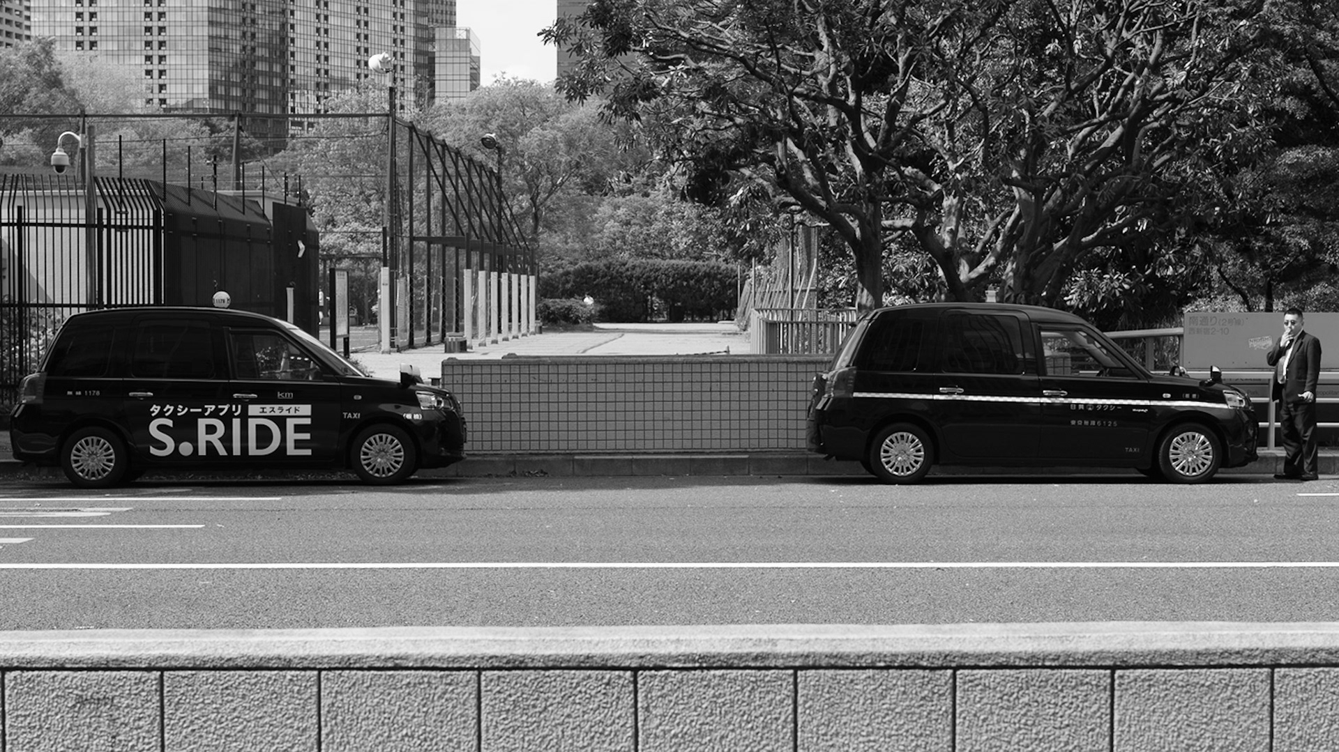 Captured by Ikeji Uju: A smoking taxi driver outside of his taxi near the Tokyo Metropolitan Government Building in Tokyo, Japan.