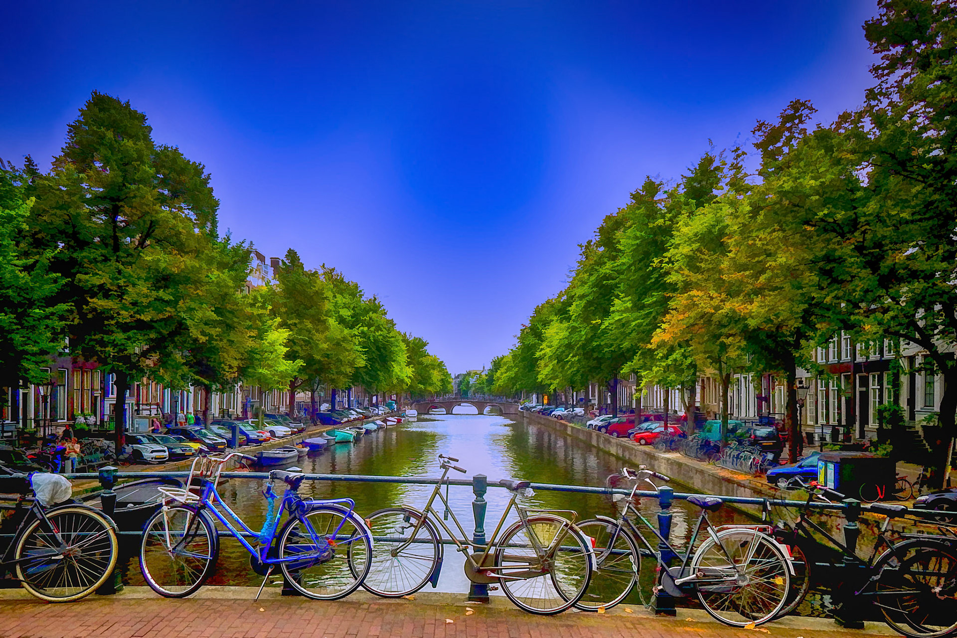 Bikes, boats, and cars parked along a canal in Amsterdam, The Netherlands