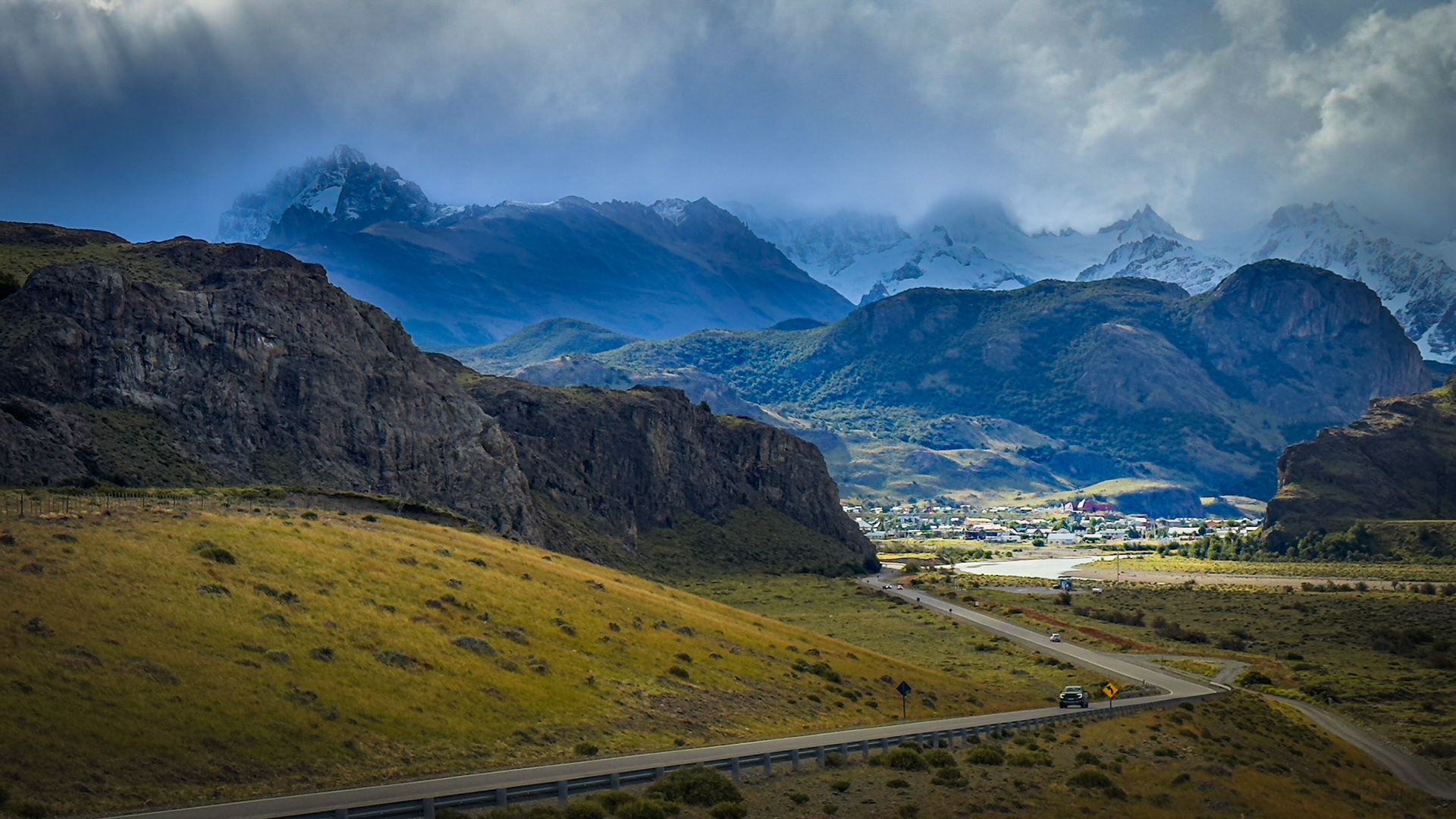 The small town of El Chalten with Mount Fitzroy, along with other mountain peaks, obscured by snow towering behind it.