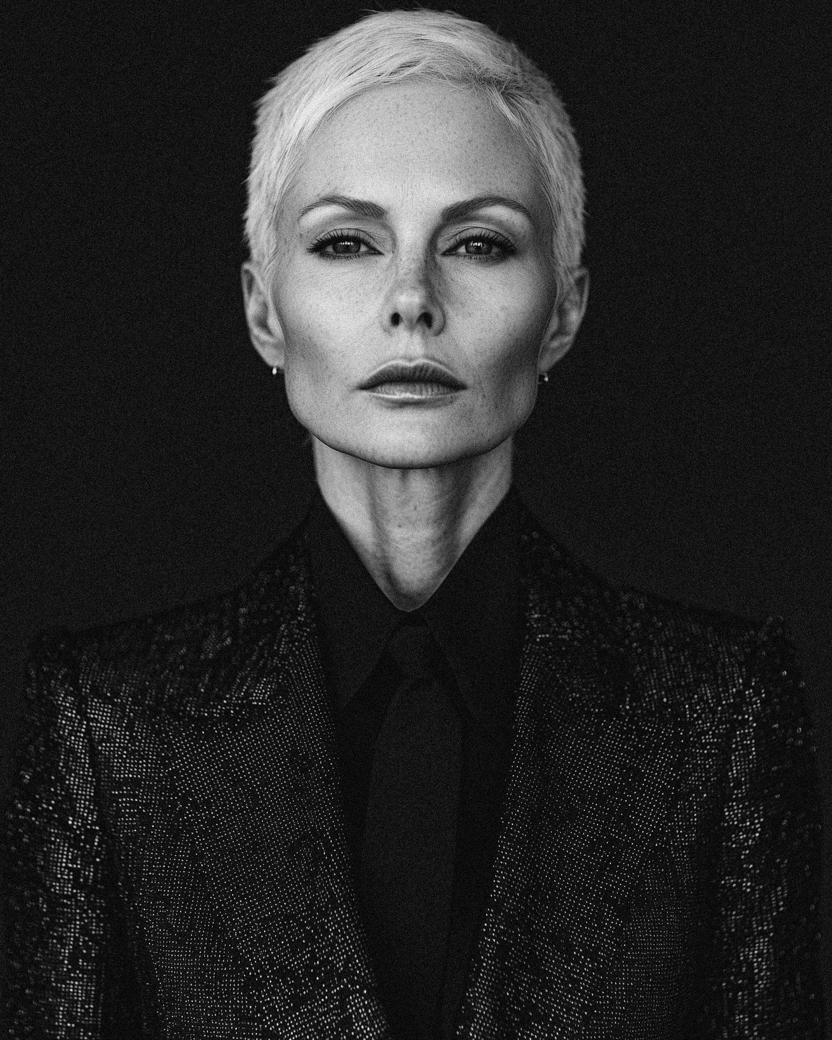 Full-body black and white portrait of a 42-year-old European woman with extremely pale skin, dressed in an elegant, structured high-fashion suit with sharp tailoring and refined details. Shot with a large-scale plate camera in the style of Nick Knight, using Fuji Acros II film simulation for rich contrasts. The lighting highlights the textures of her attire and her dignified expression, creating a timeless, sophisticated look --chaos 10 --ar 4:5 --quality 2 --stylize 500 --v 6.1 Job ID: 05034fb8-7570-4cf4-8882-7aa1d75e60b3