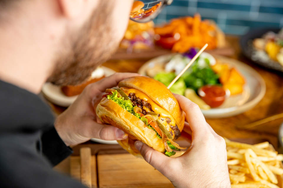 Hands holding a burger above a serving of fries