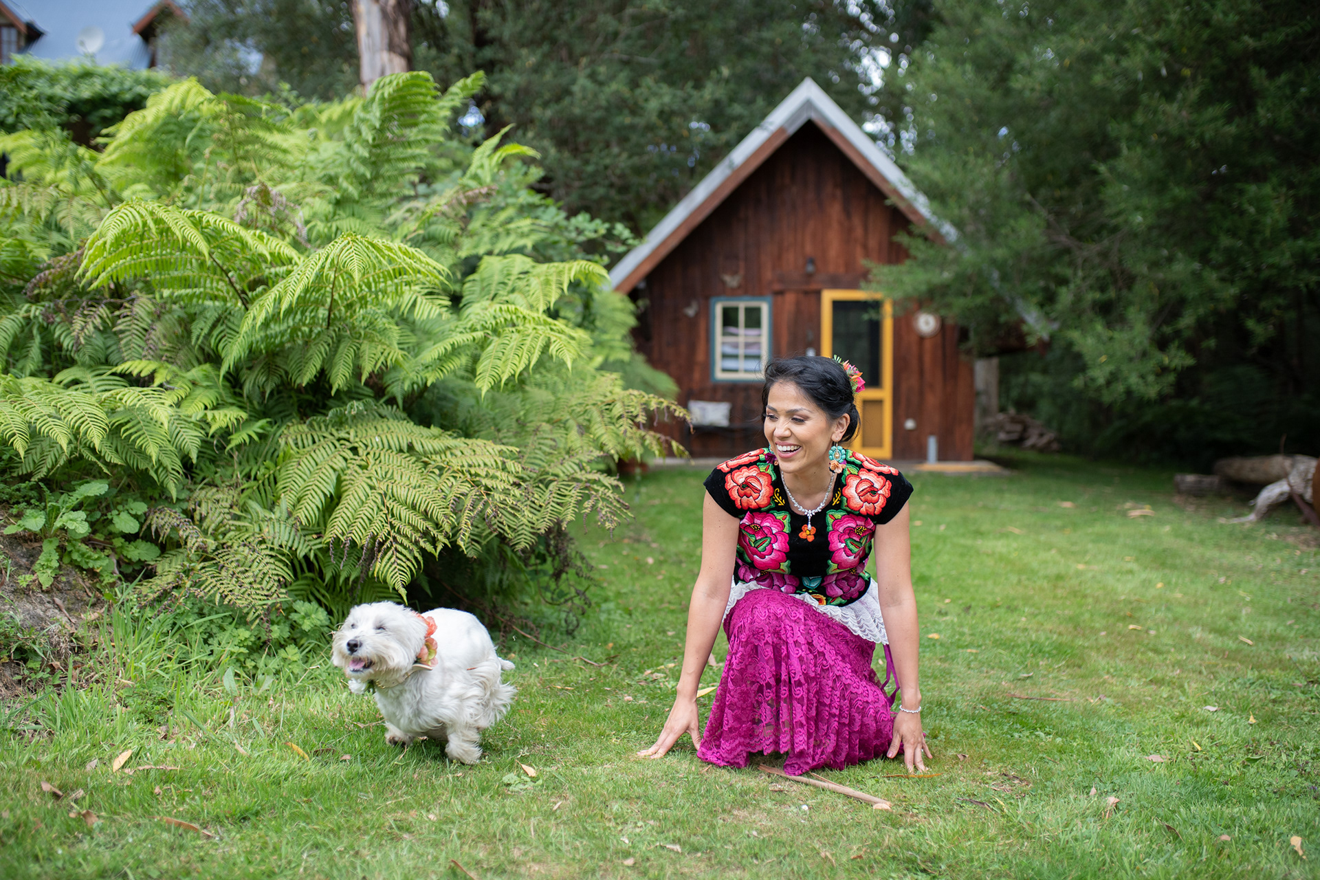Couple in colourful outfits standing in a garden with their dog