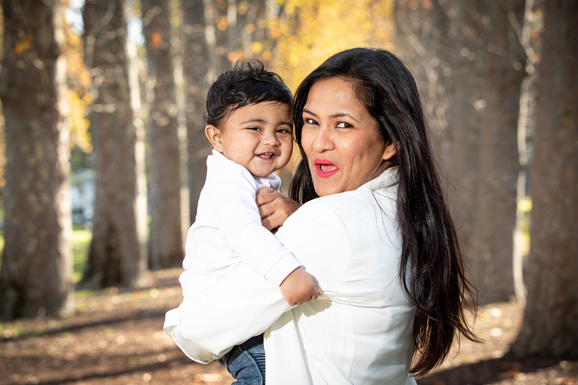 Parent holding a child among sunlit trees