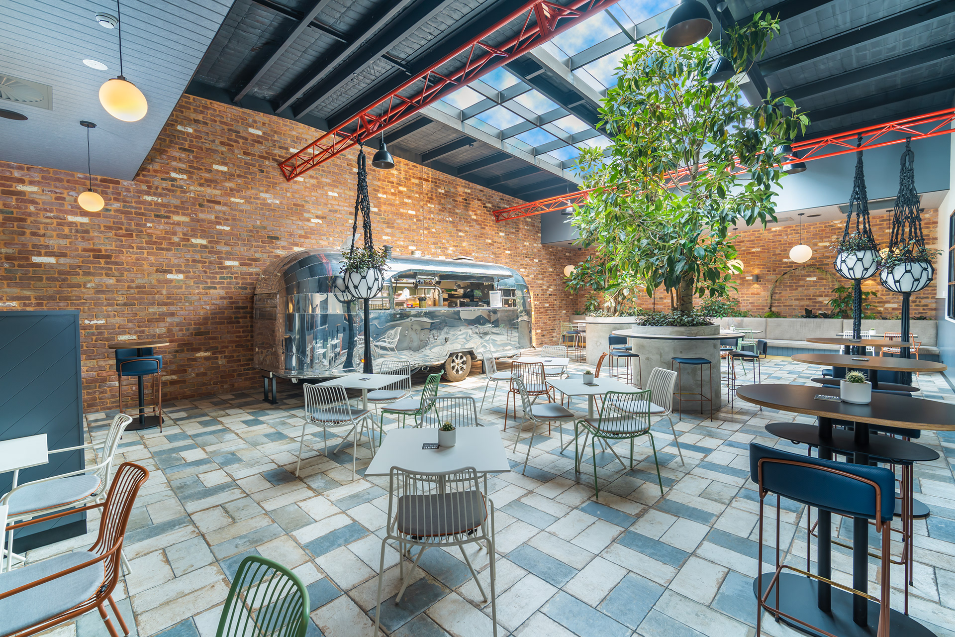 Restaurant dining area with skylights, greenery and brick walls