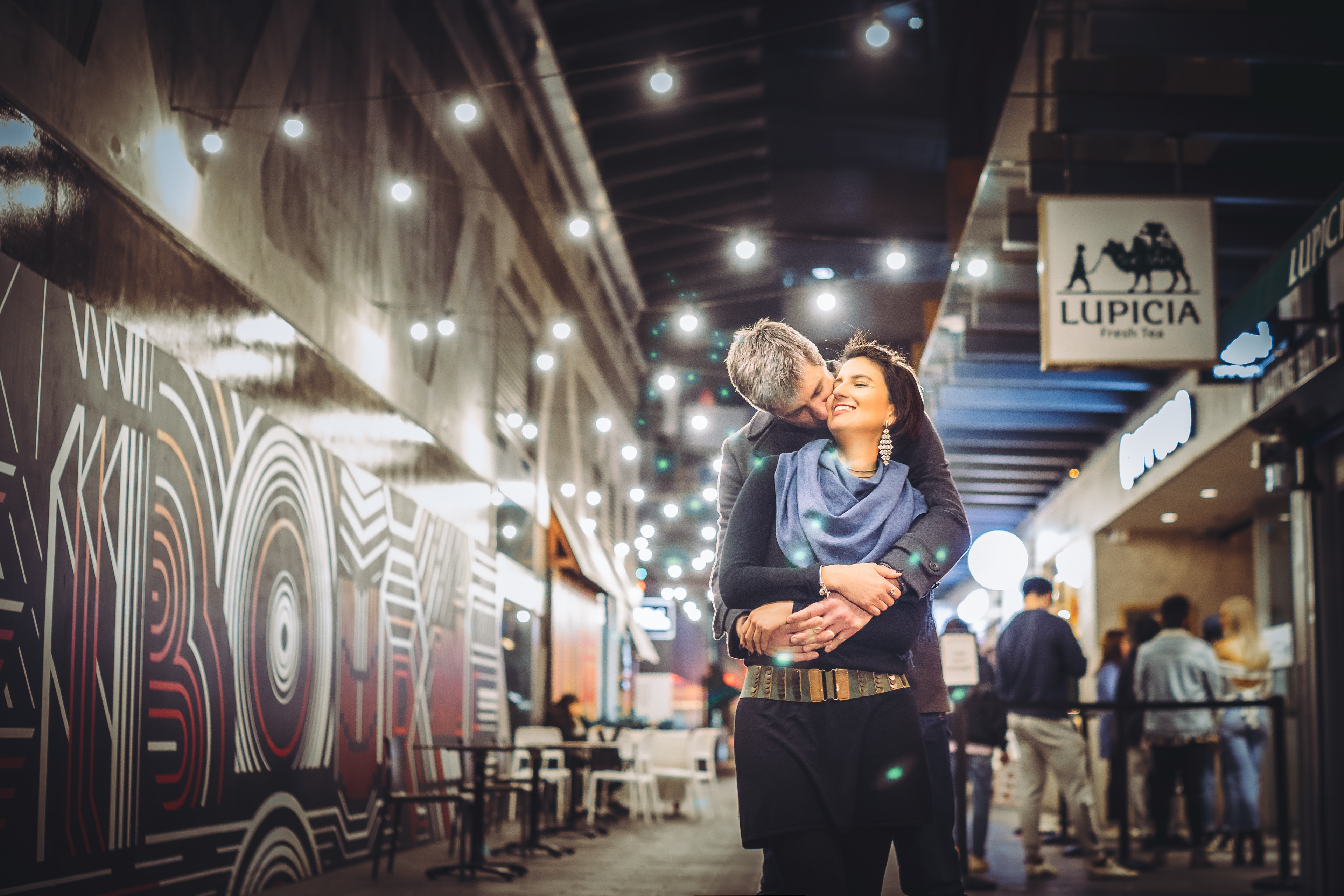 Couple embracing beneath string lights at night