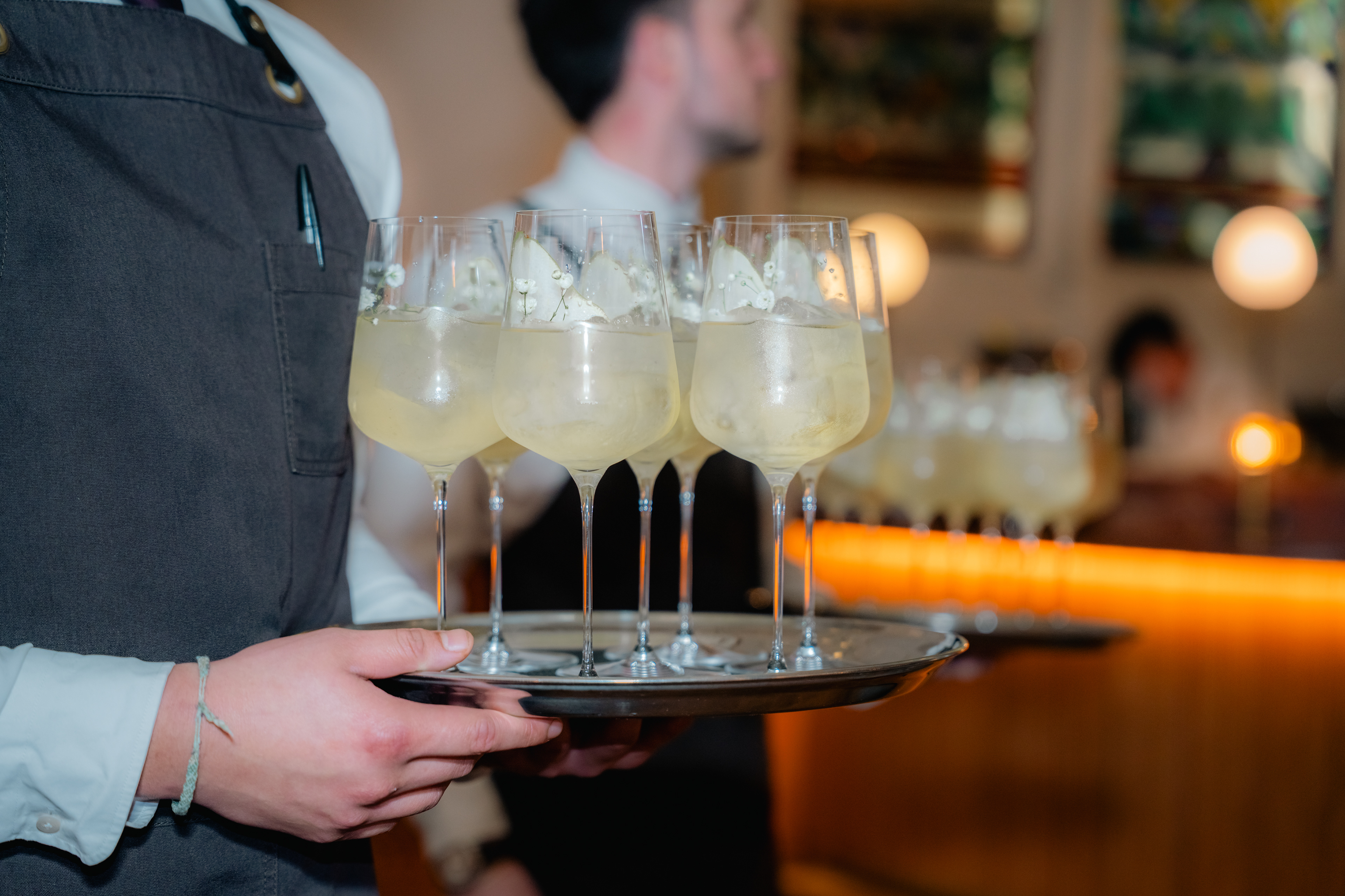 Waiter carrying a tray of pale cocktails