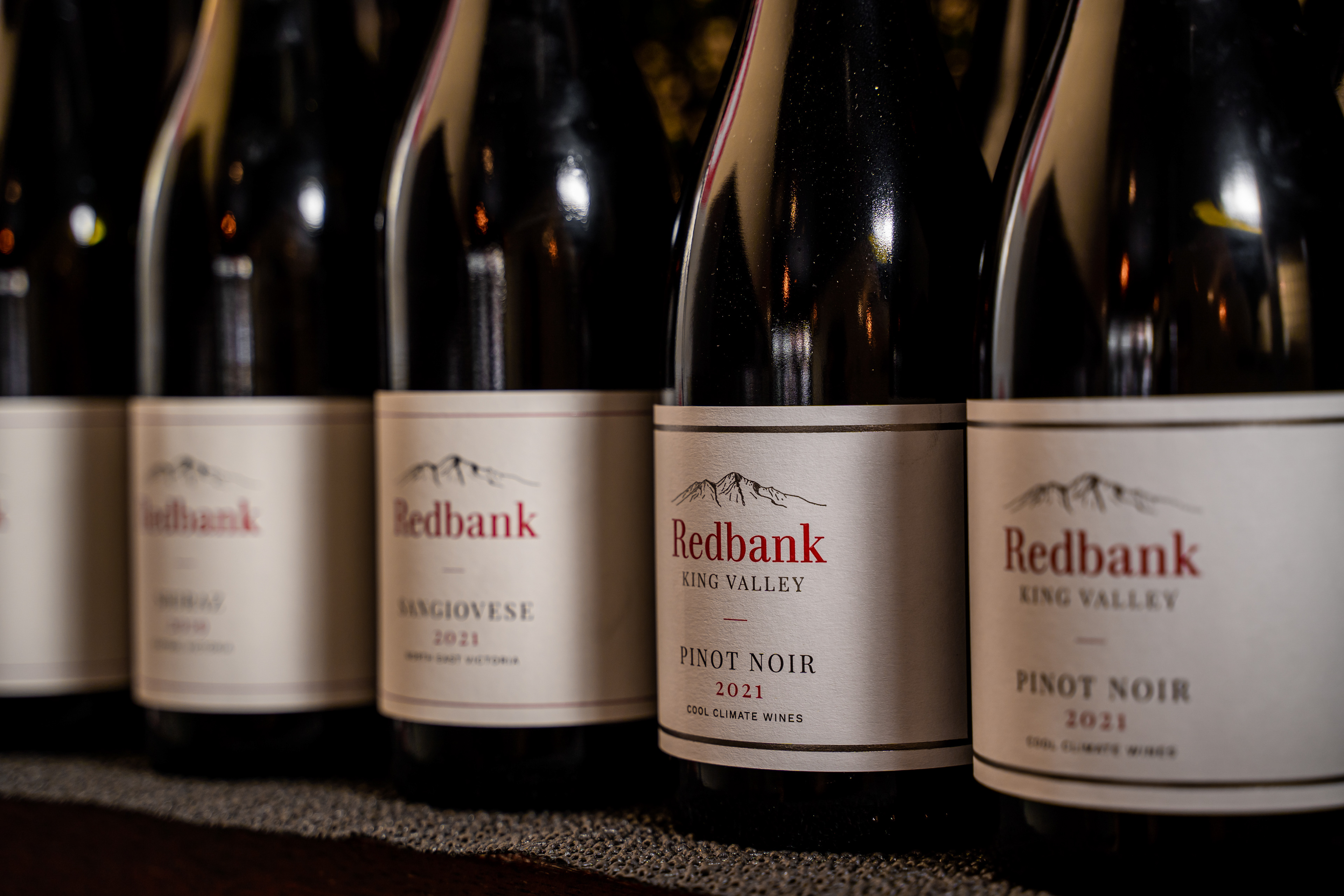 Row of red wine bottles with labels facing forward