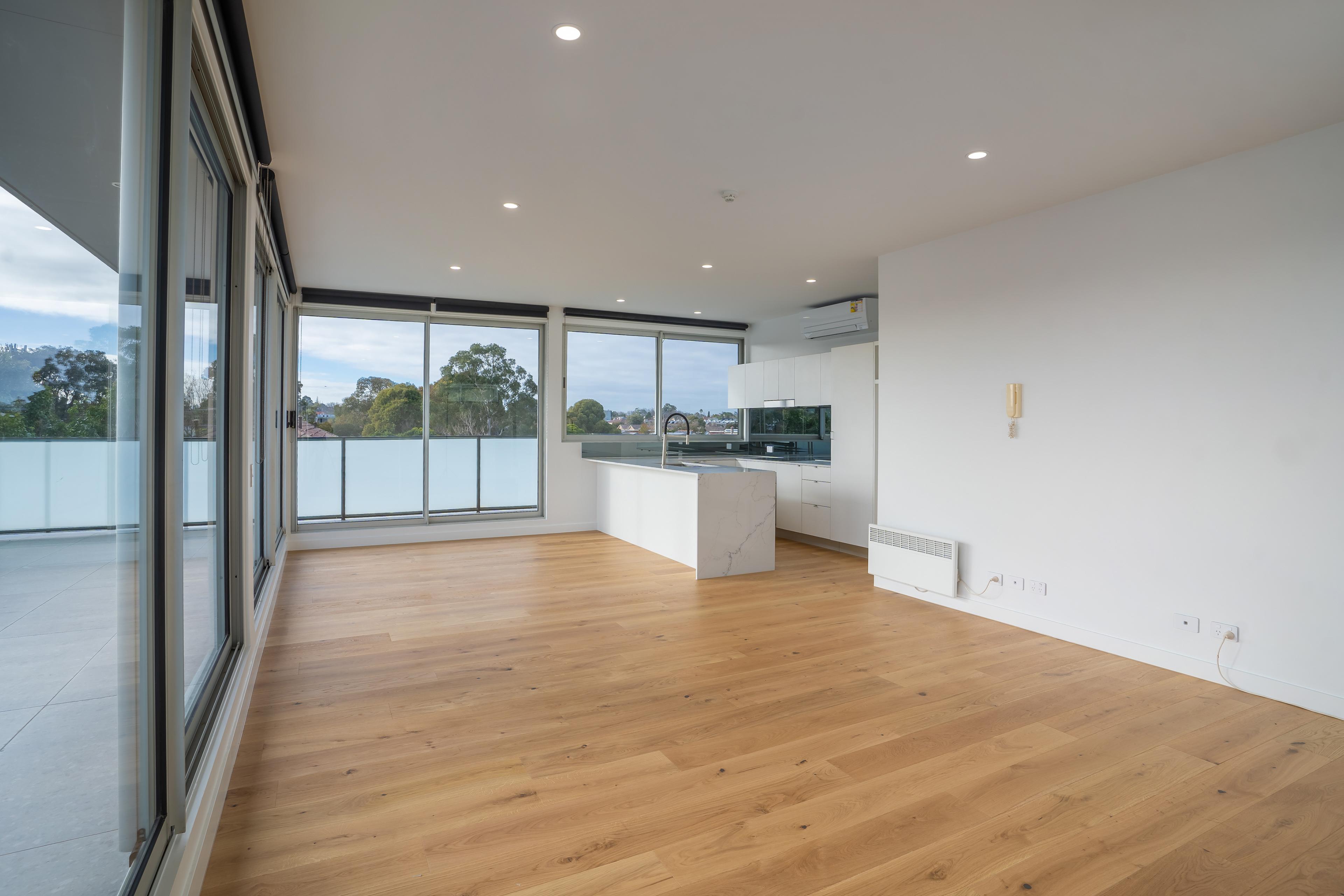 Empty apartment living area with timber floors and large windows