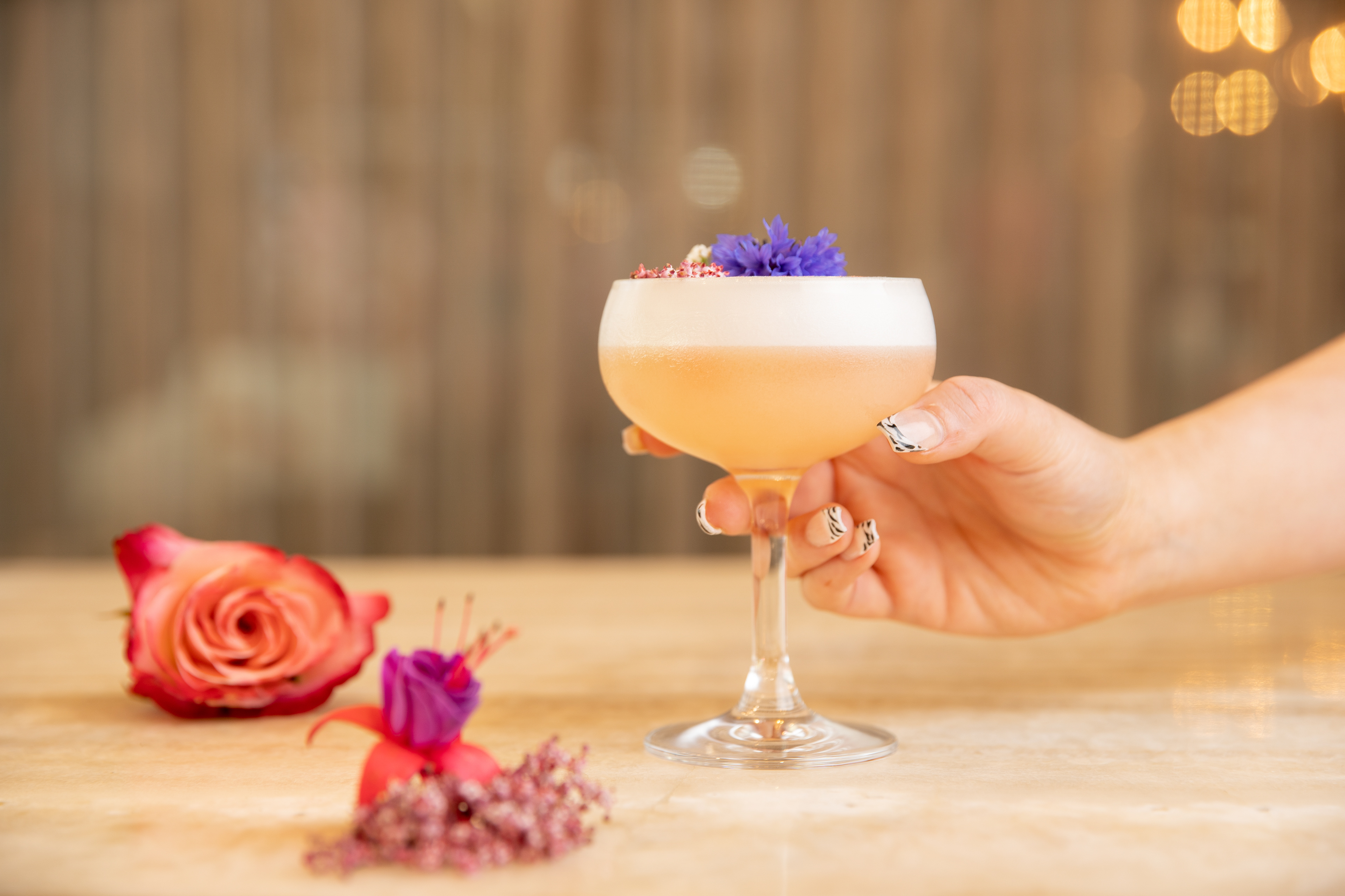 Pale cocktail garnished with a purple flower