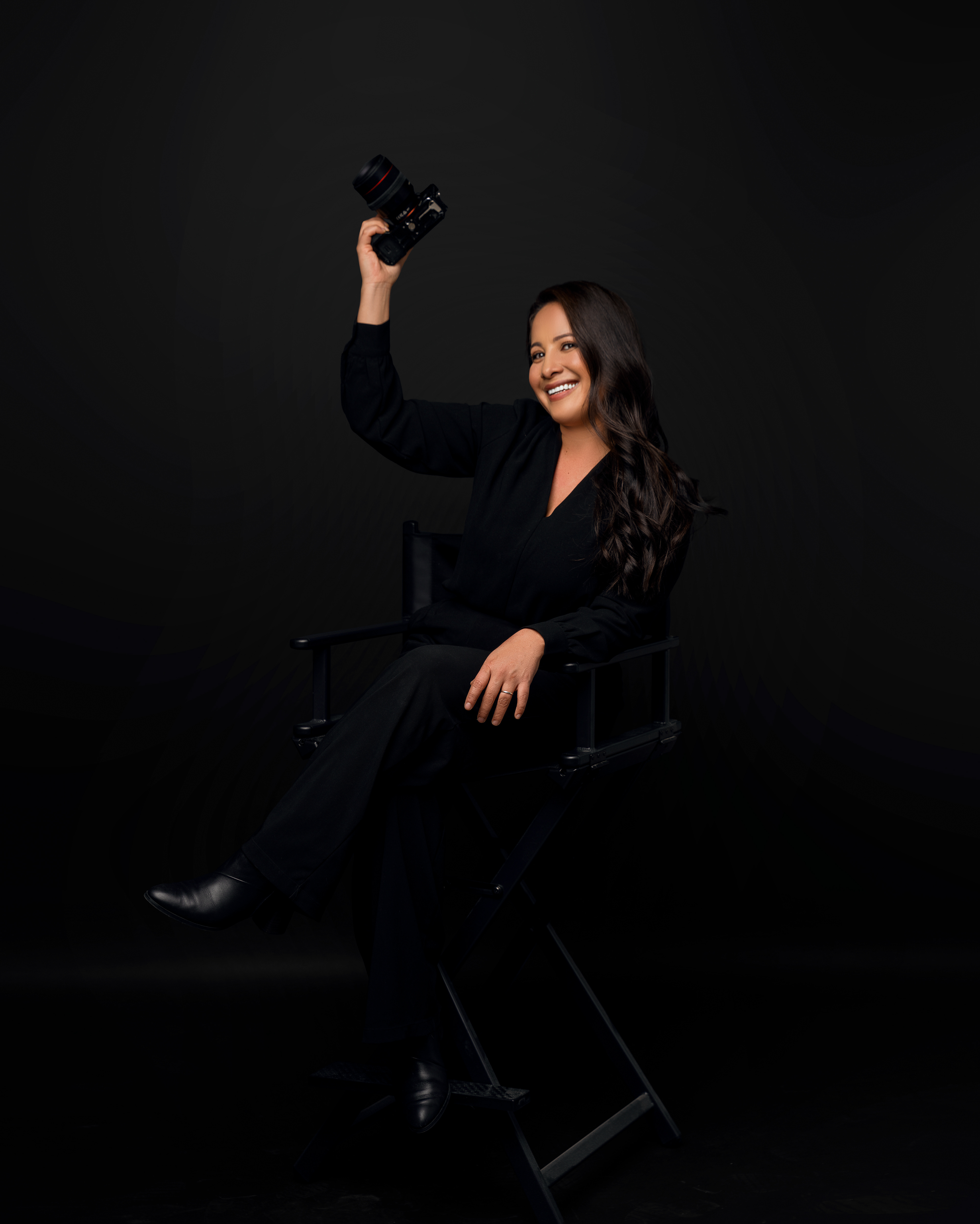 Seated studio portrait with one arm raised against black