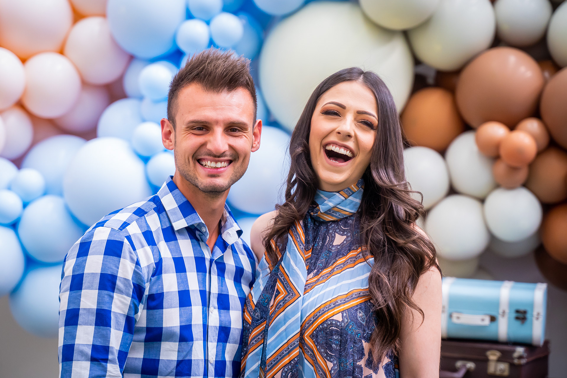 Two guests laughing beside a balloon backdrop