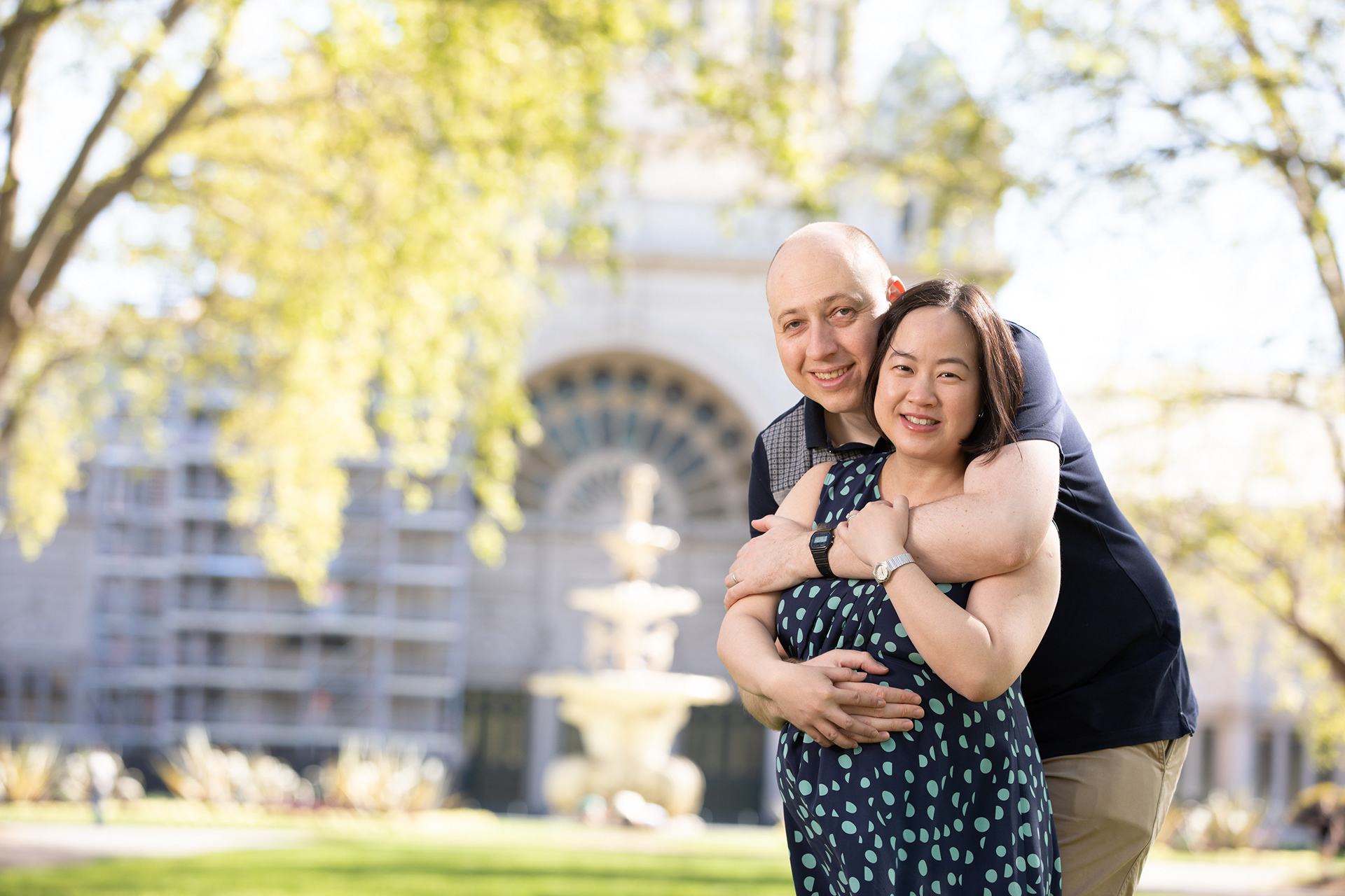 Parent lifting a baby in a sunlit park