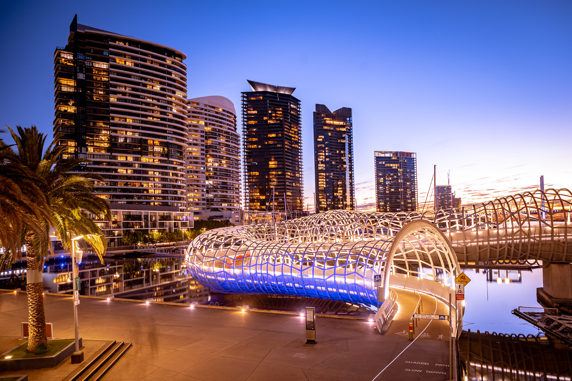 Illuminated pedestrian bridge and waterfront buildings at night