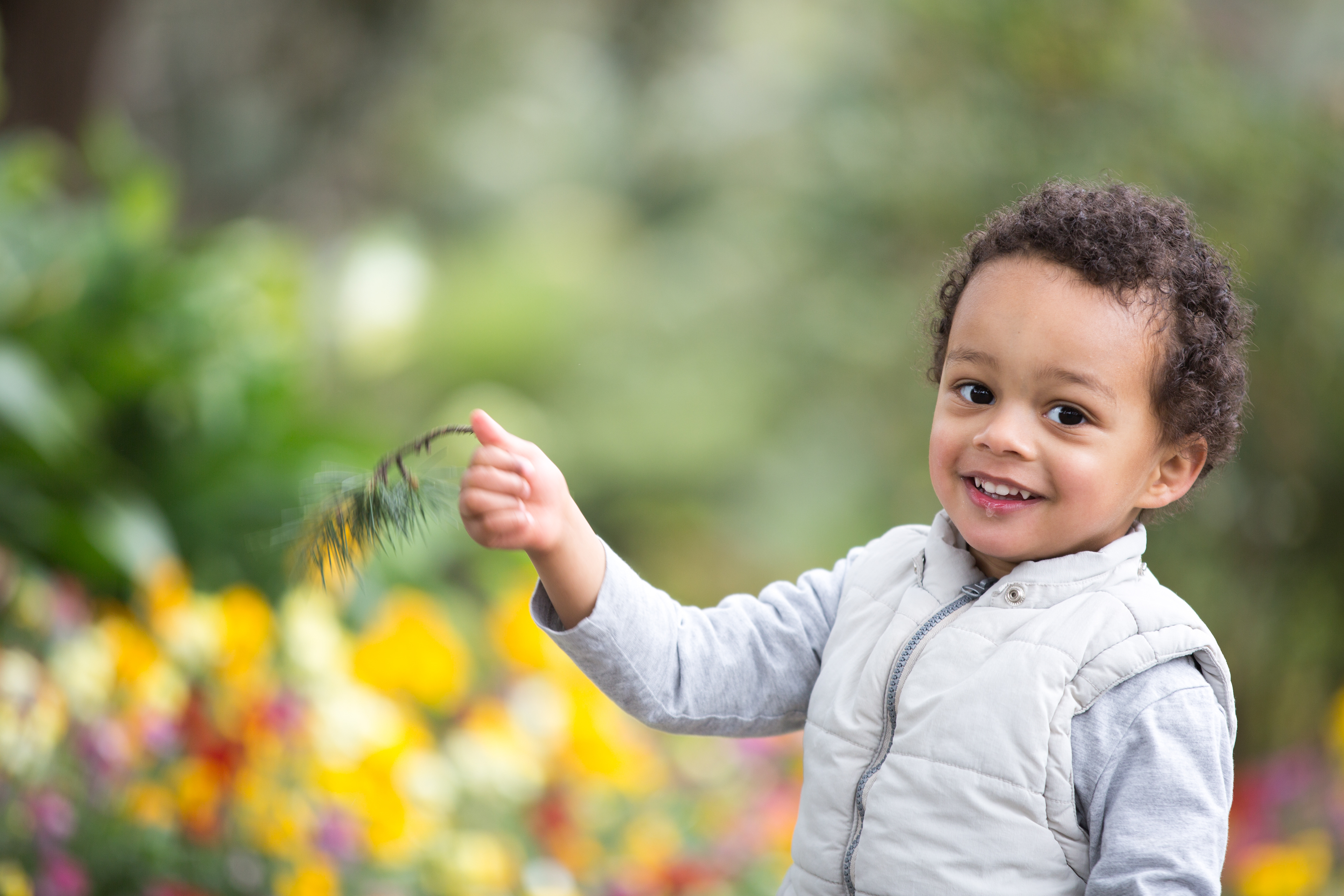 Child blowing dandelion seeds in a park