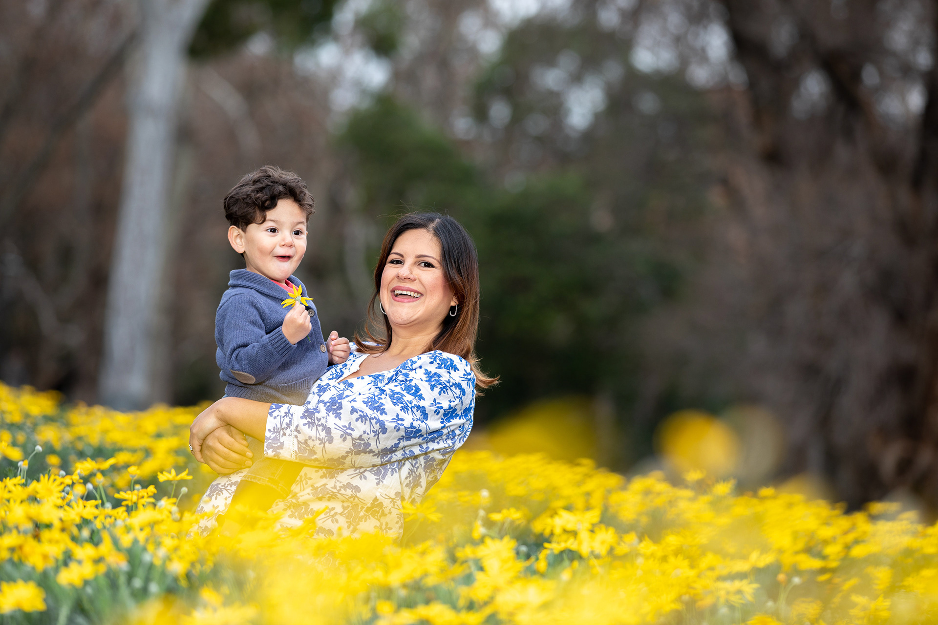 Parent holding a child in a field of yellow flowers