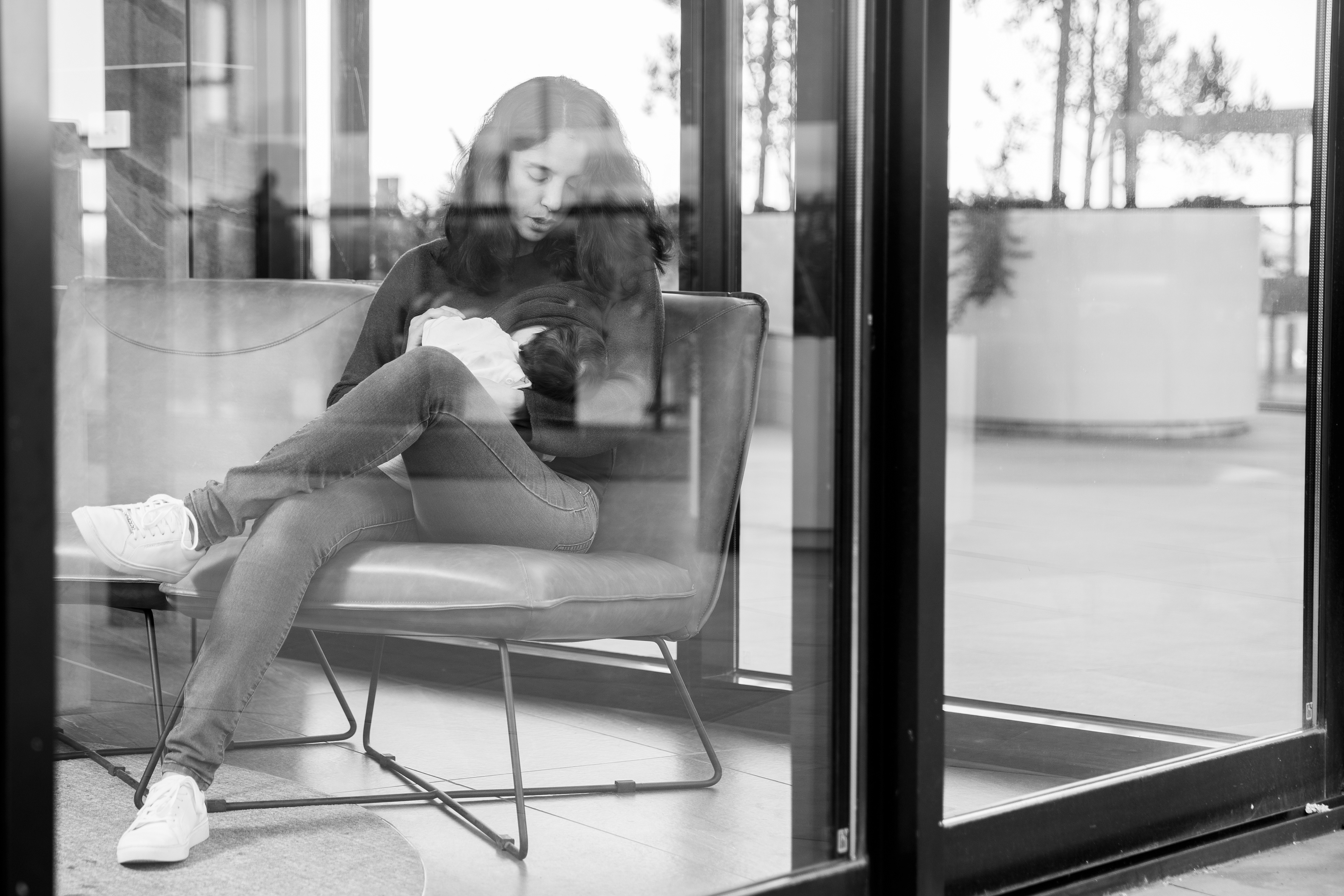 Black-and-white portrait of a parent holding a baby by a doorway