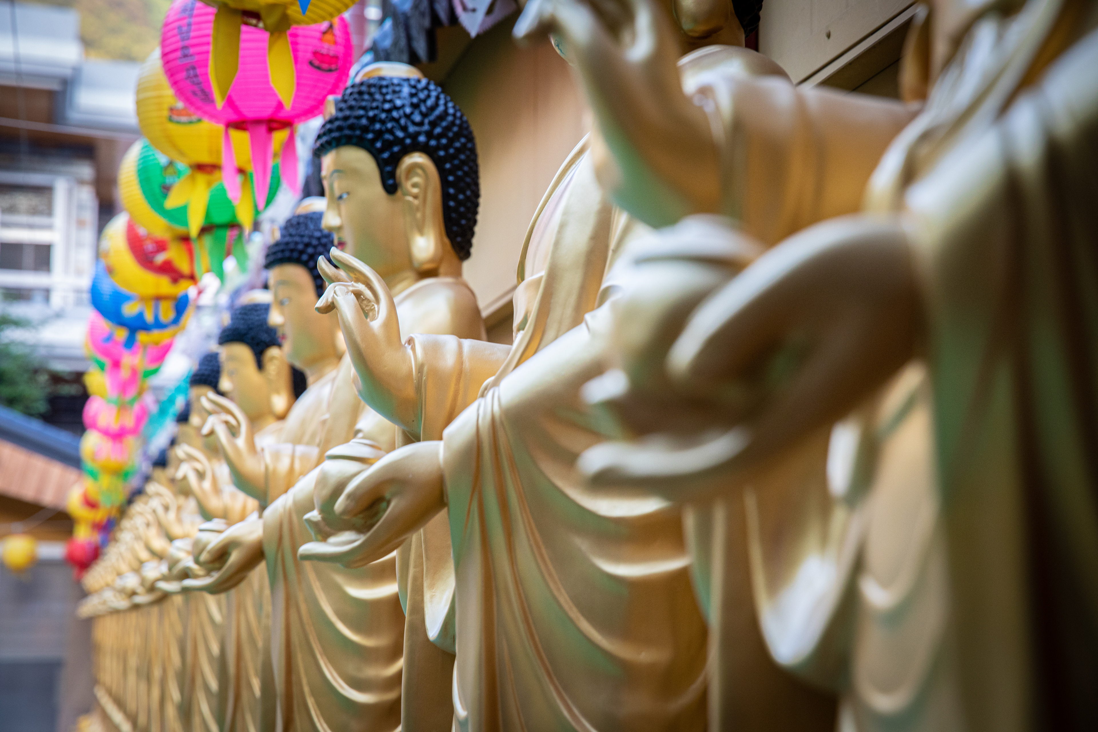 Row of golden statues beneath colourful lanterns