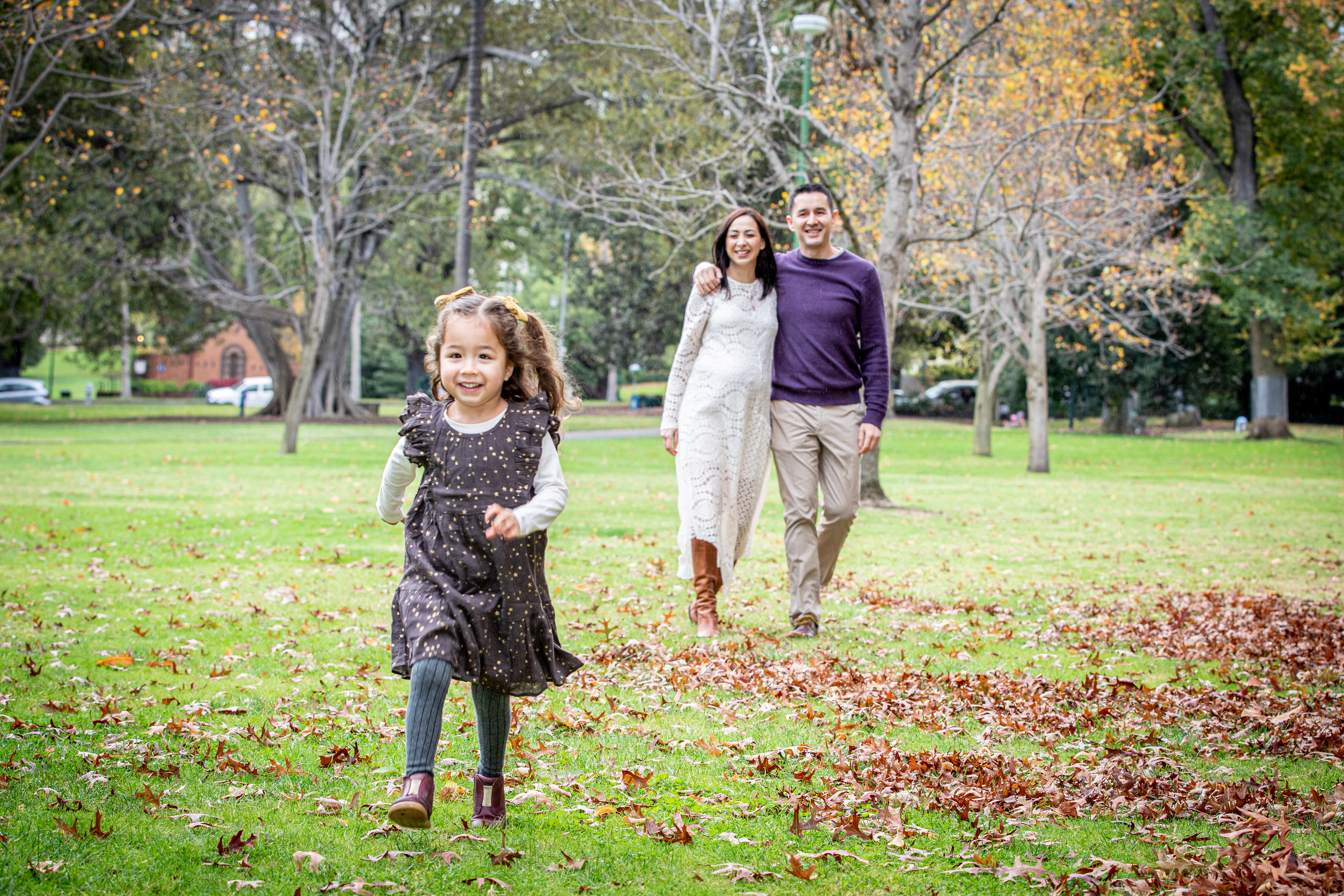 Child running towards the camera with family behind