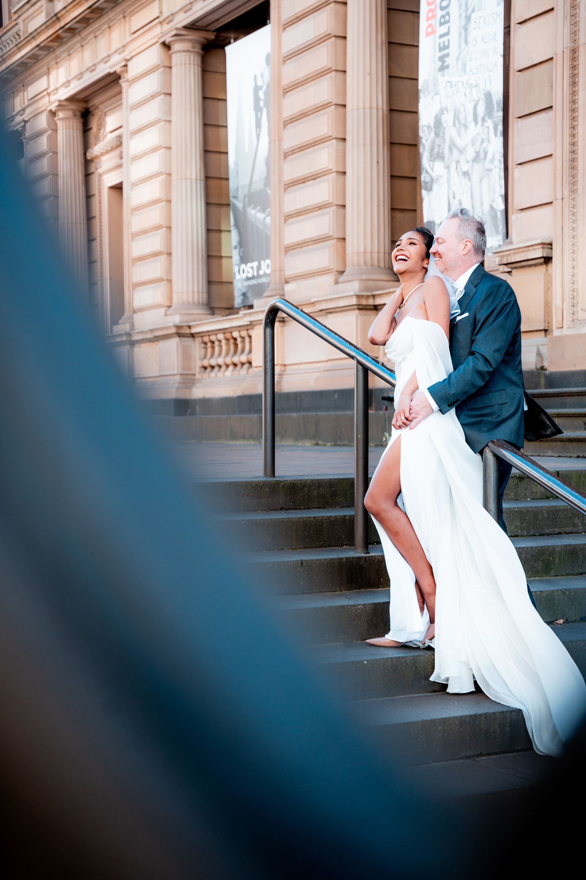 Wedding couple posing on the steps of a stone building