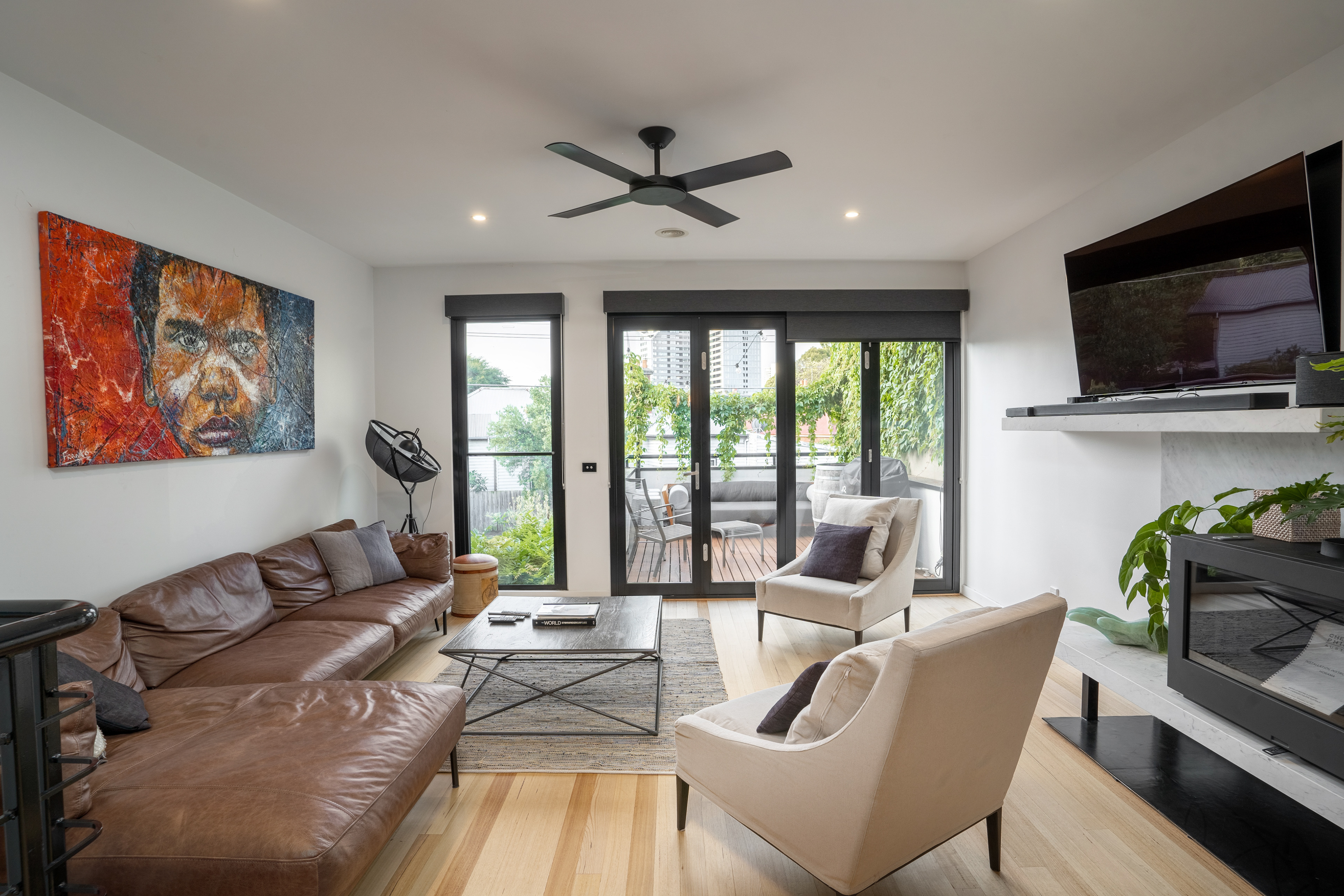 Living room with artwork, a ceiling fan and garden doors