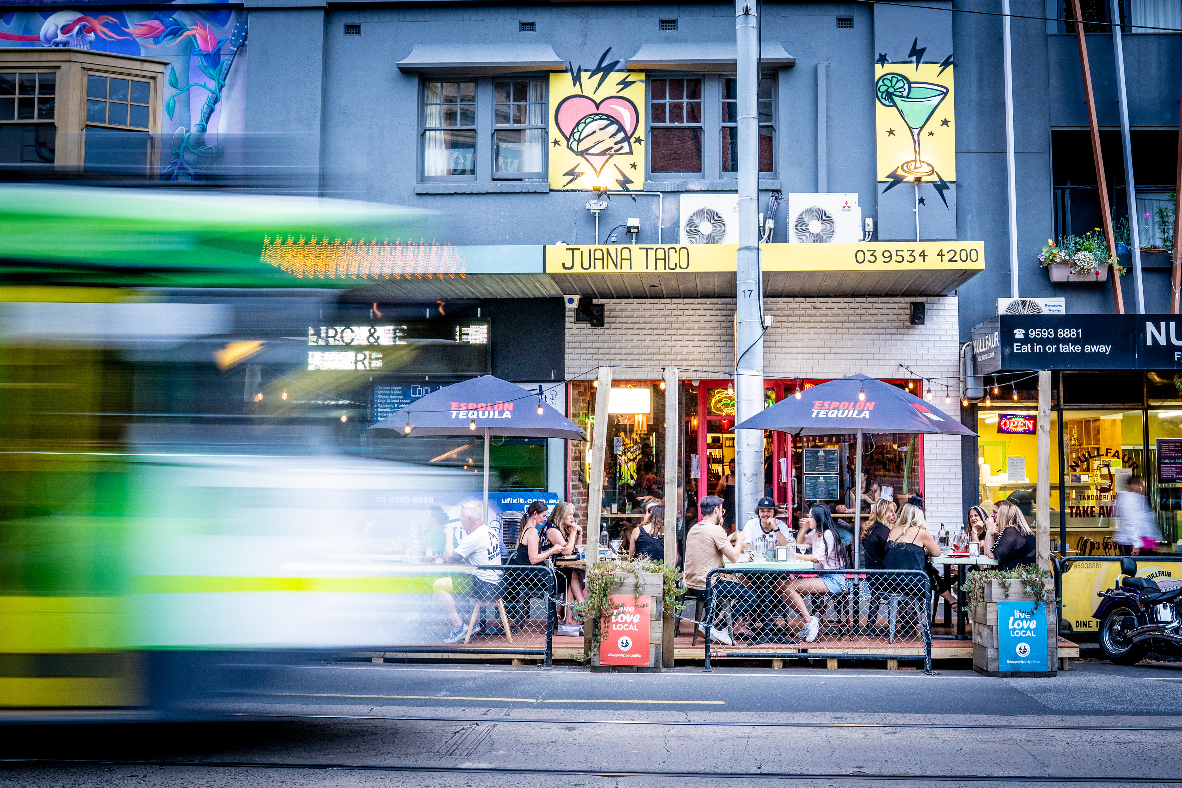 Cafe storefront behind a passing green tram