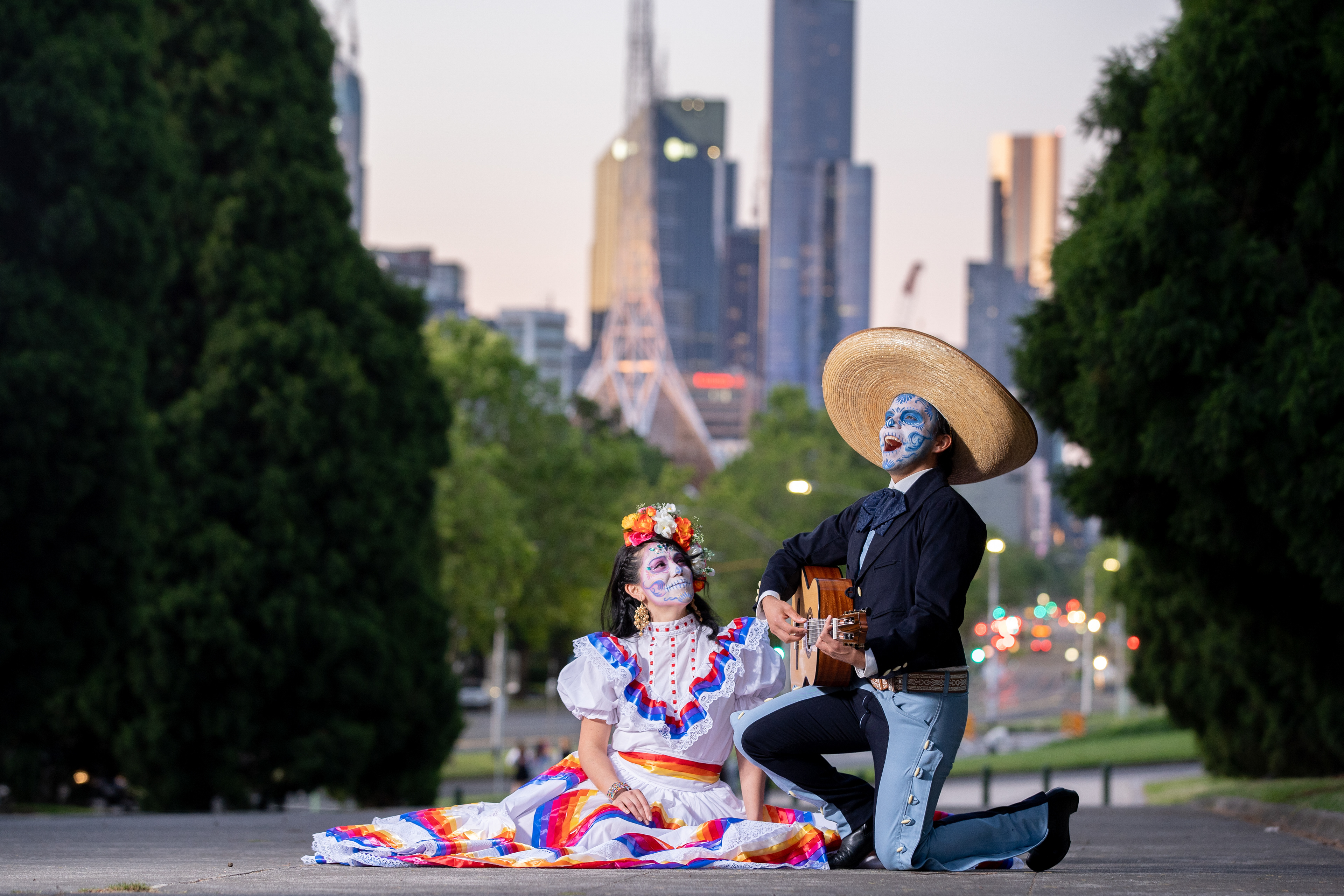 Couple in colourful traditional-style outfits with the city behind