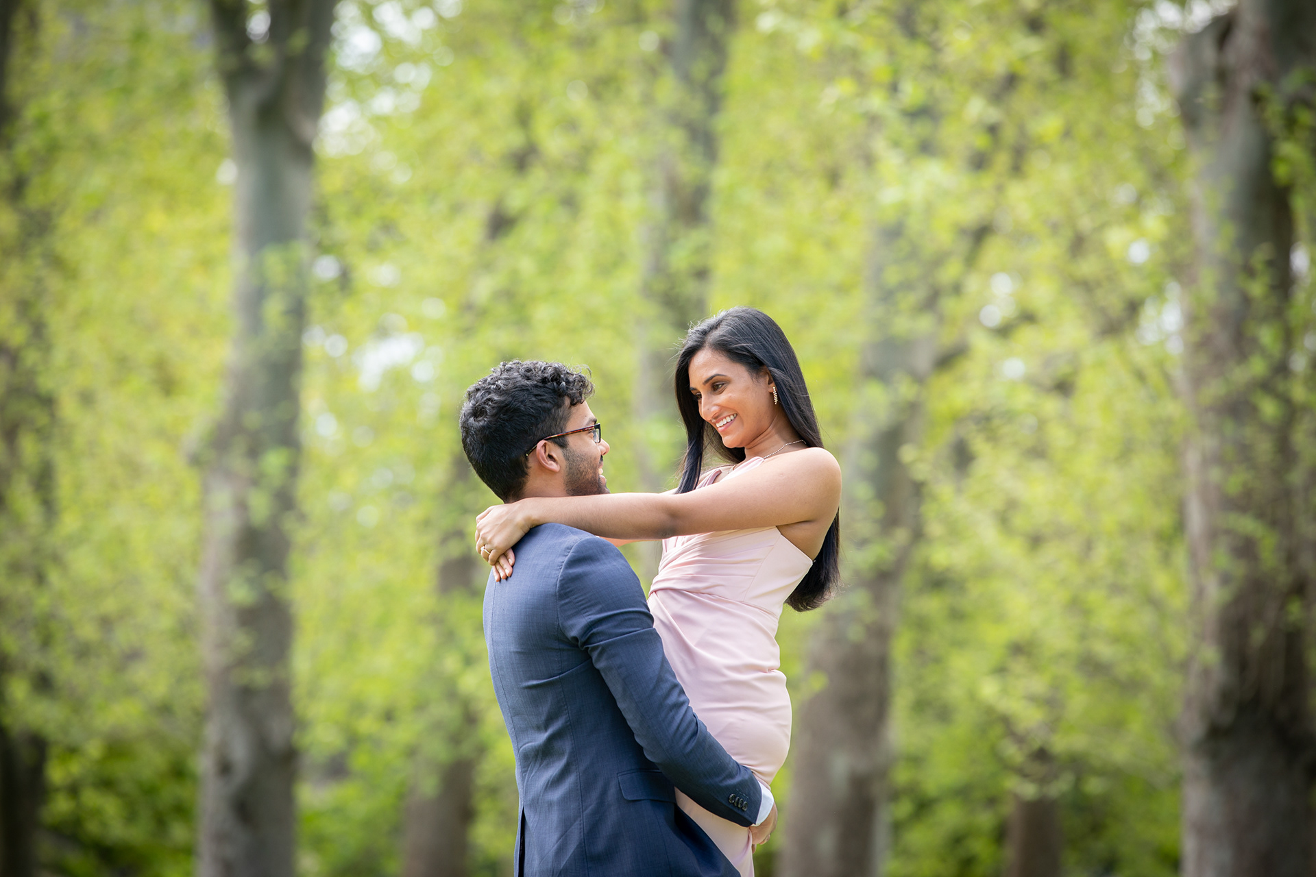 Couple embracing beneath soft green foliage
