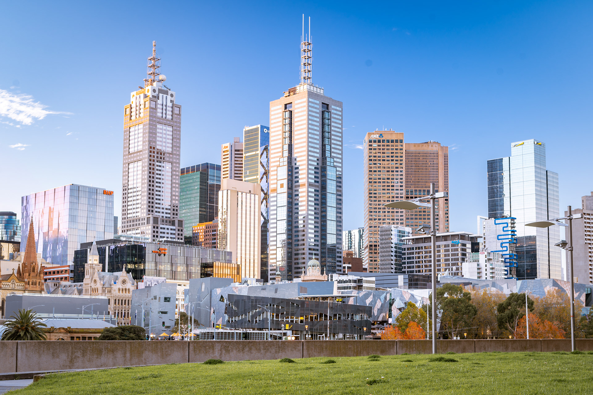 Sunlit Melbourne skyline above a riverside park