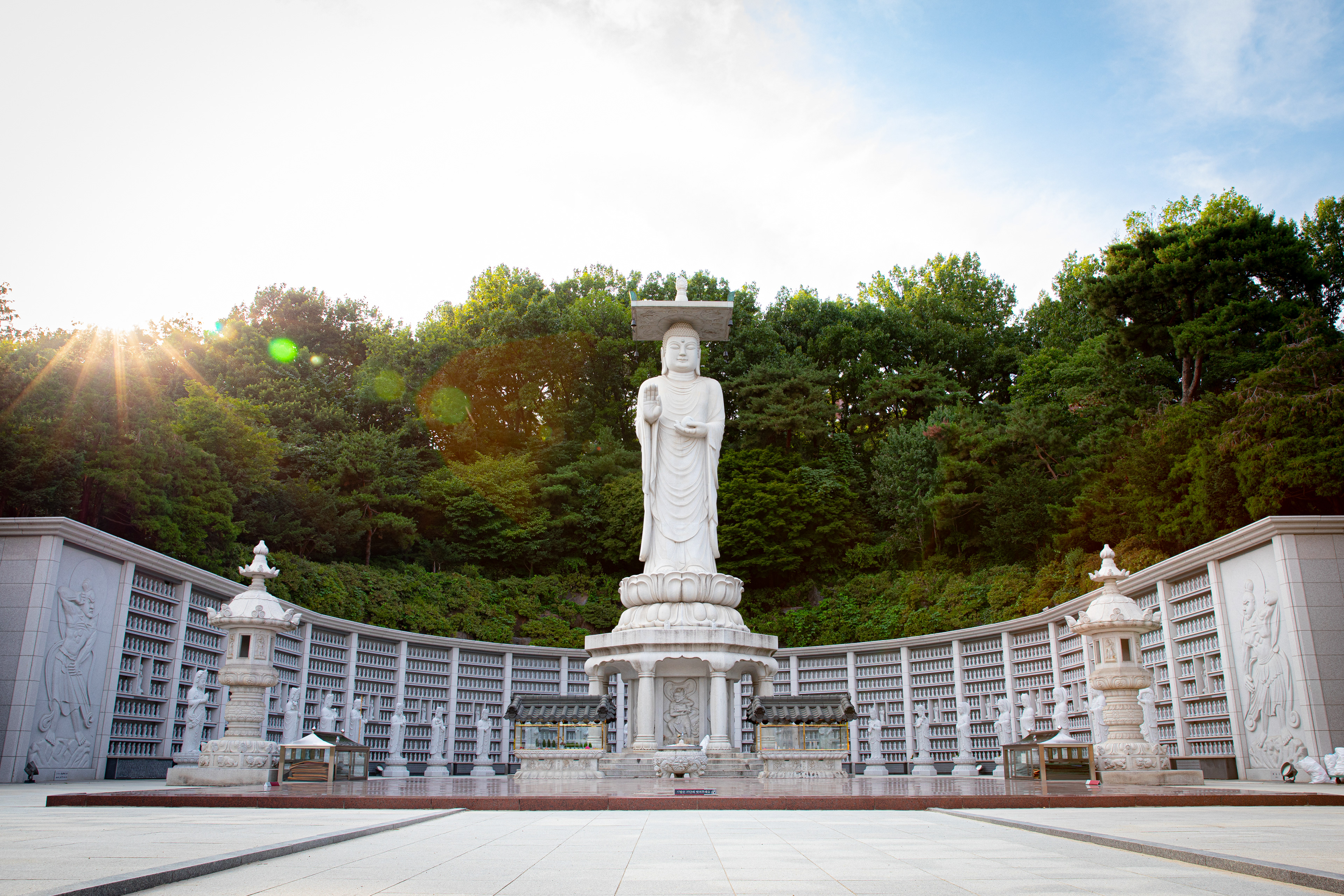Temple courtyard with a white statue and forested hills