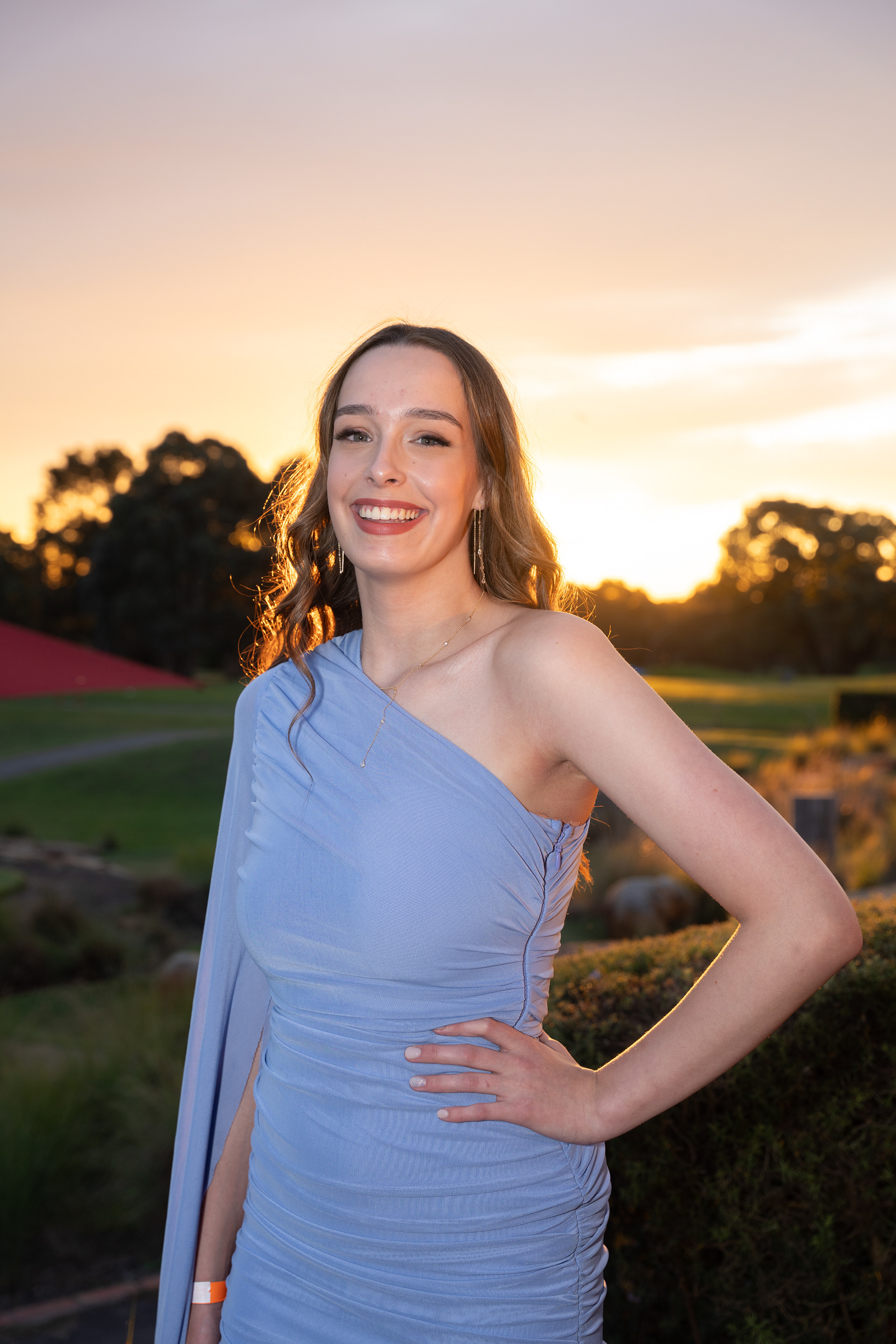 Guest in a blue dress posing outdoors at sunset