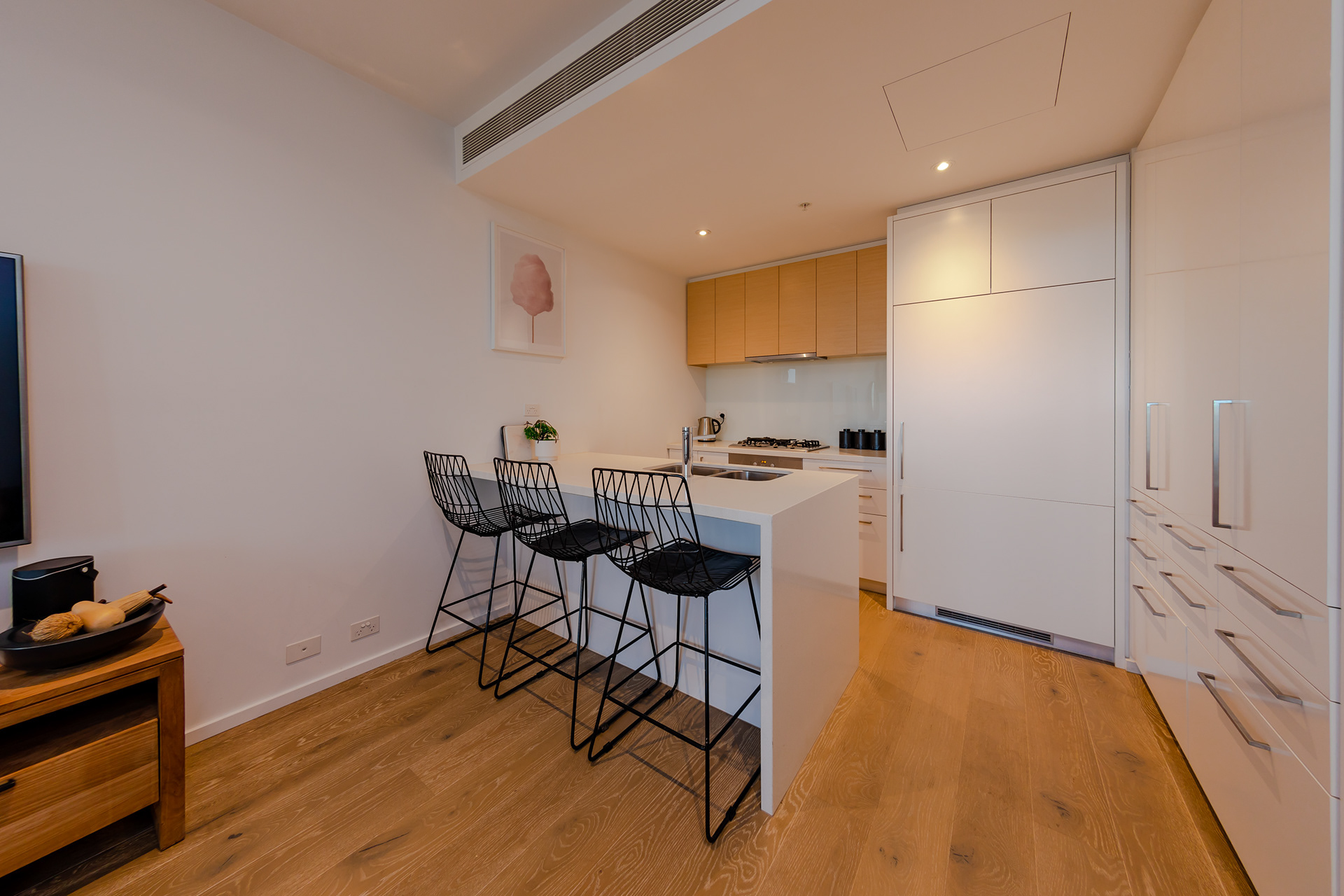 Compact white kitchen with an island and bar stools
