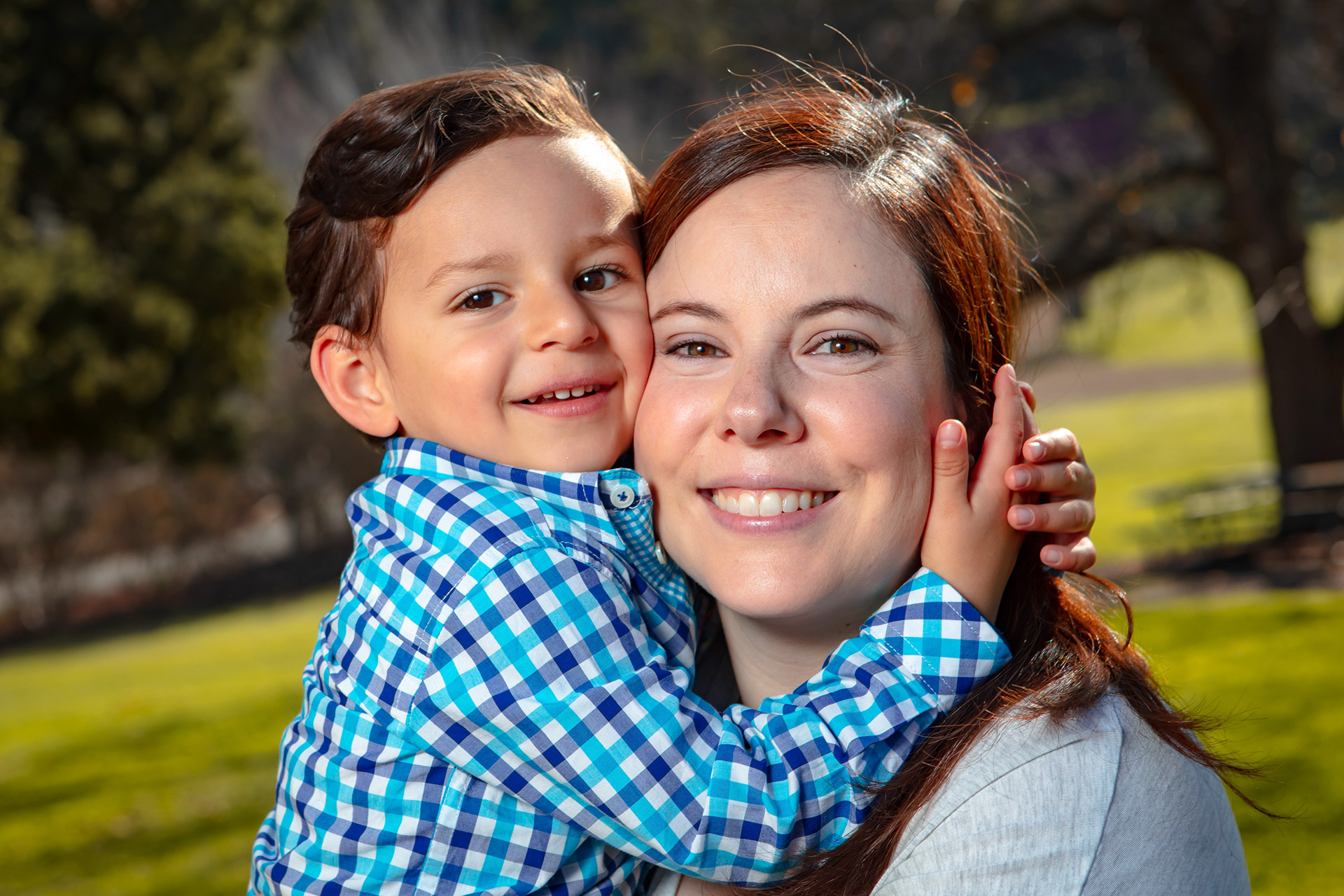 Child hugging a parent around the neck outdoors