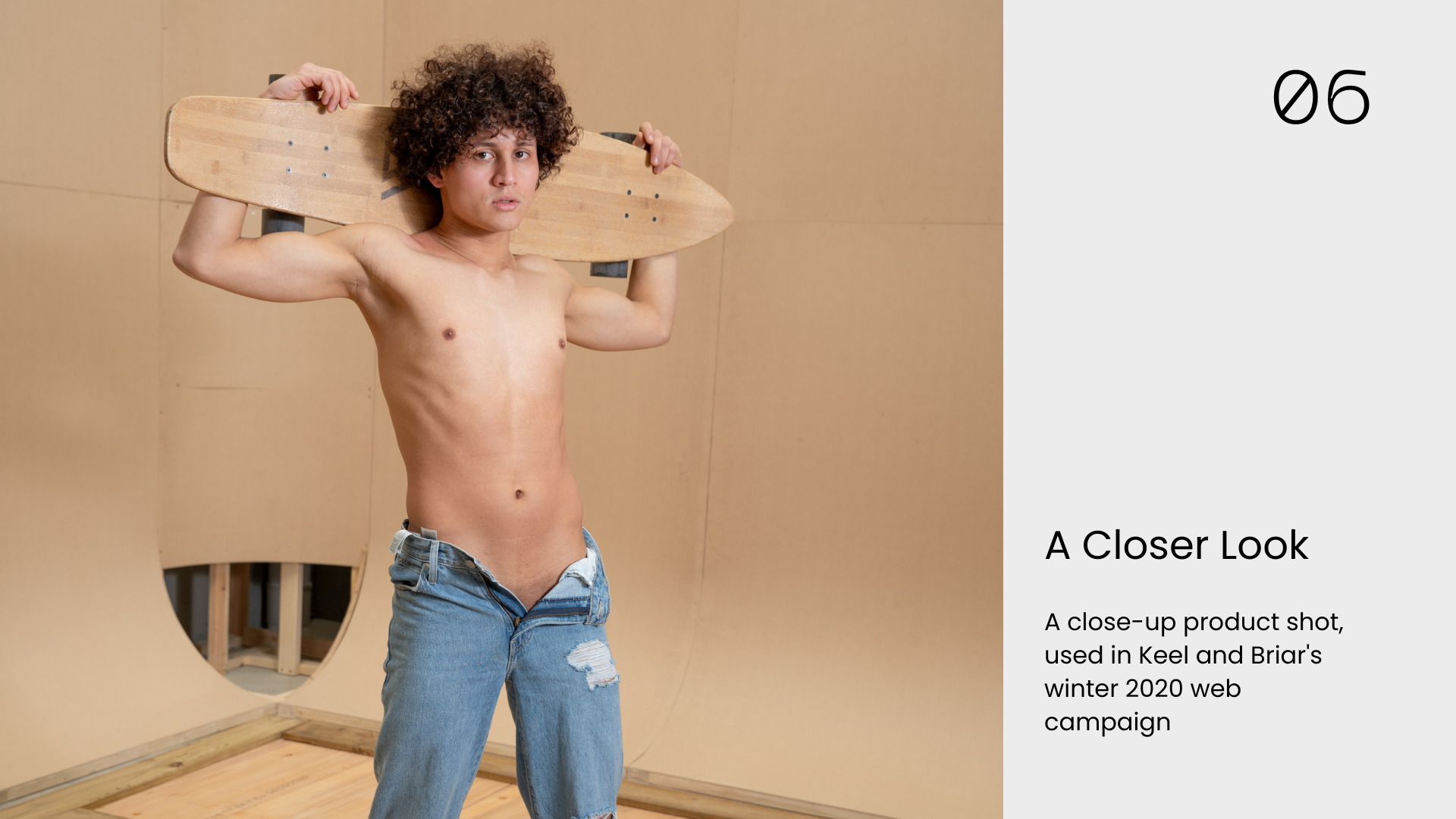 James Tapiero posing in jeans with a wooden skateboard across his shoulders