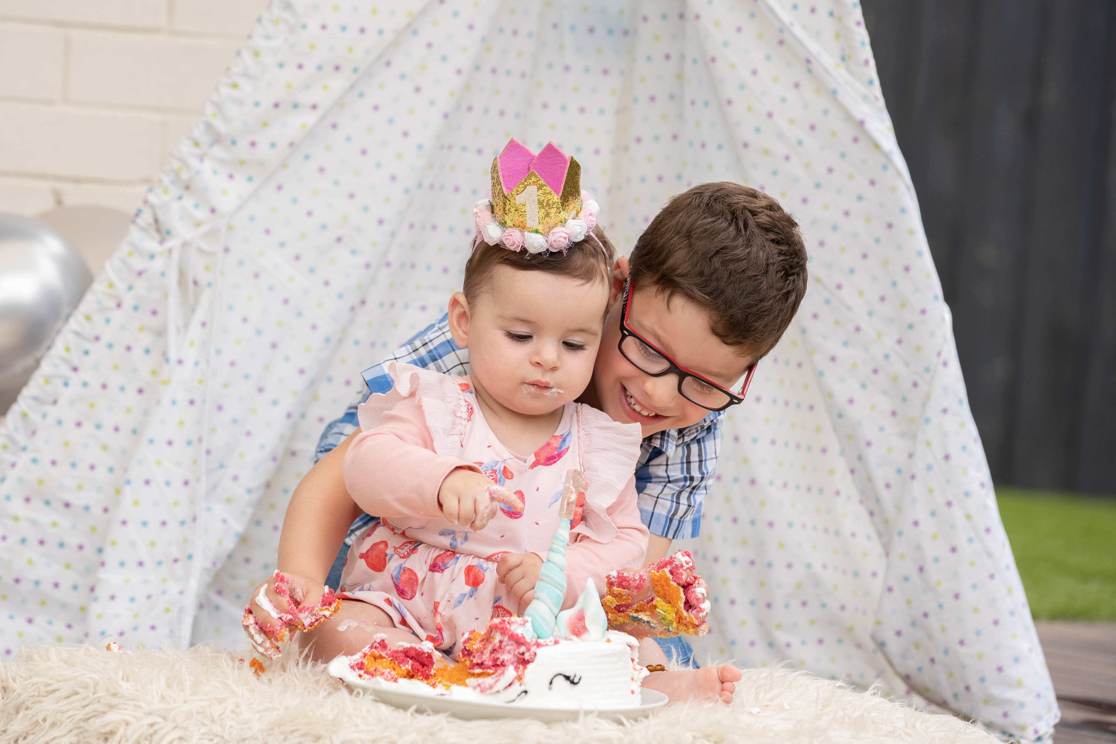 Child exploring a birthday cake during a cake smash session