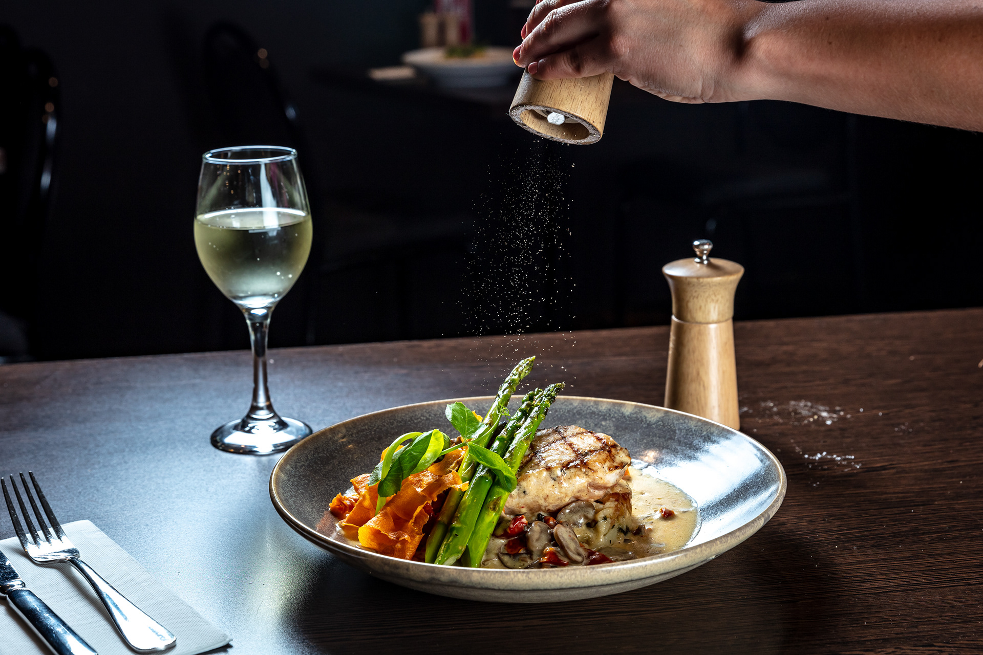 Seasoning being added to a plated restaurant dish
