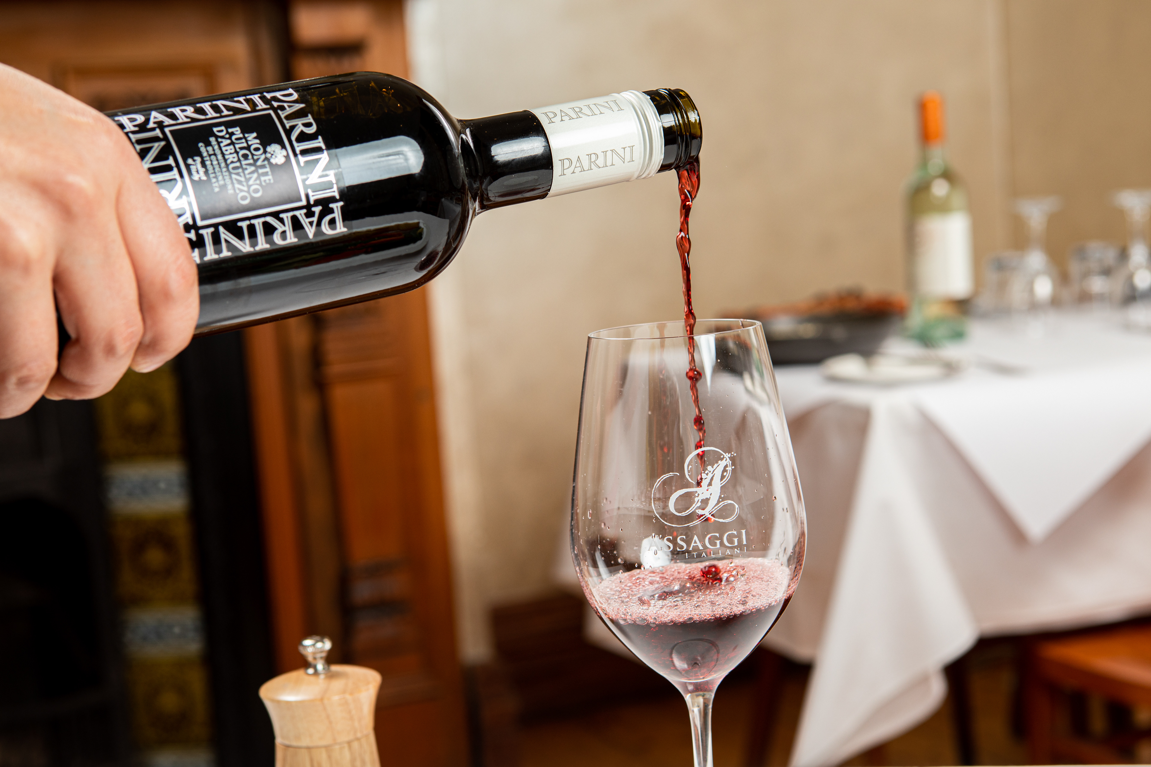 Red wine being poured into a glass at a dining table
