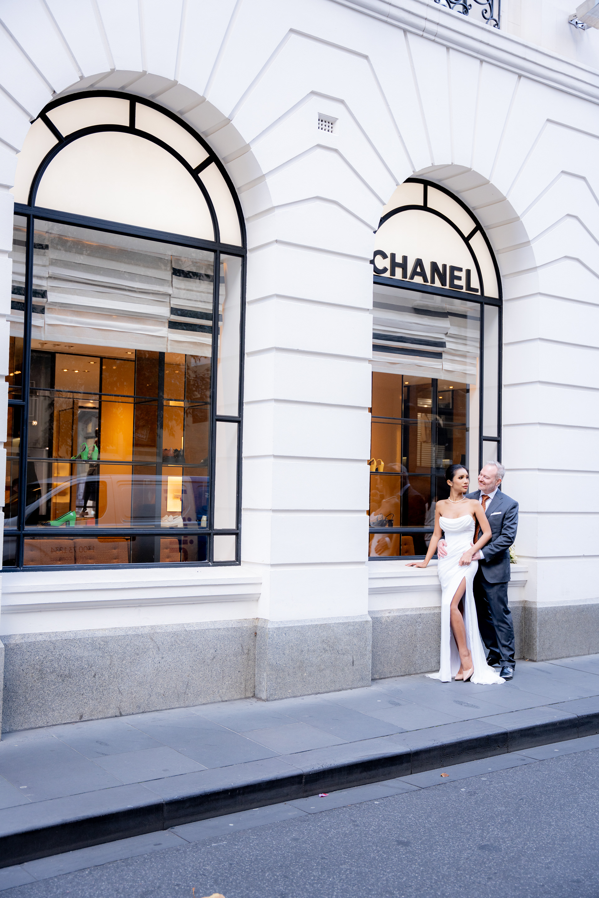 Wedding couple standing outside a building with tall arched windows
