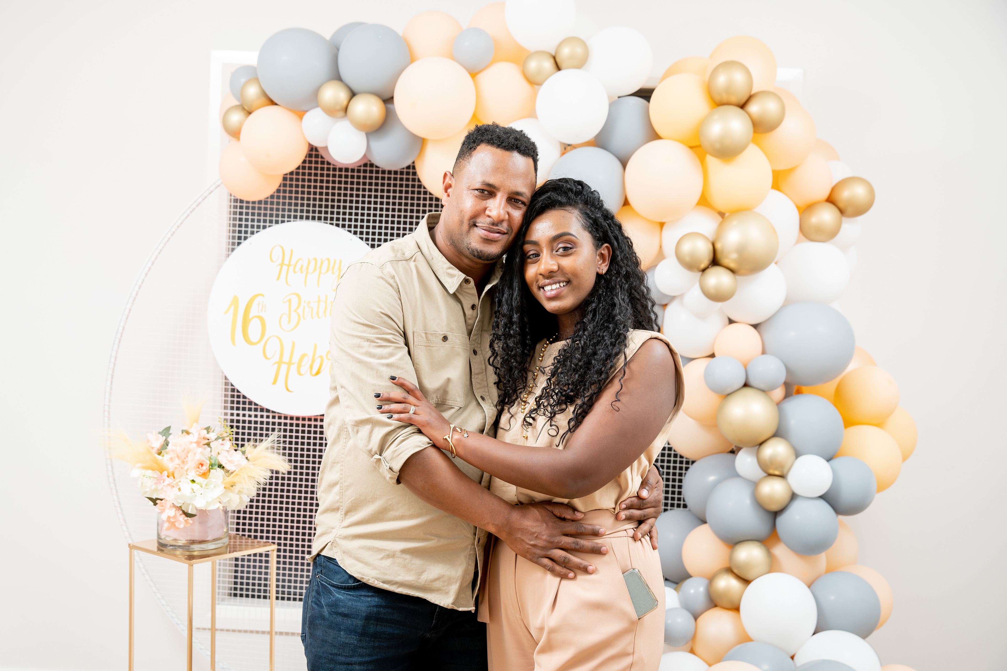 Couple smiling together in front of party decorations