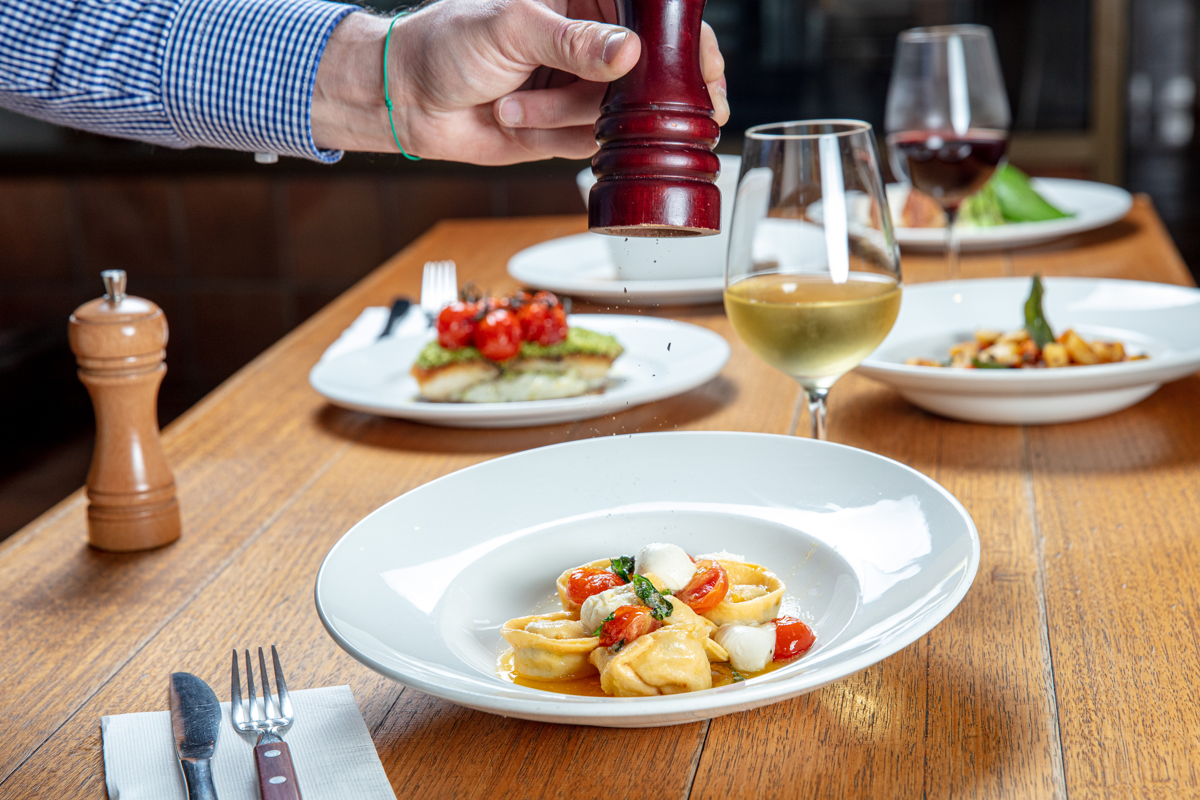 Guest dining at a restaurant table with wine and plated food