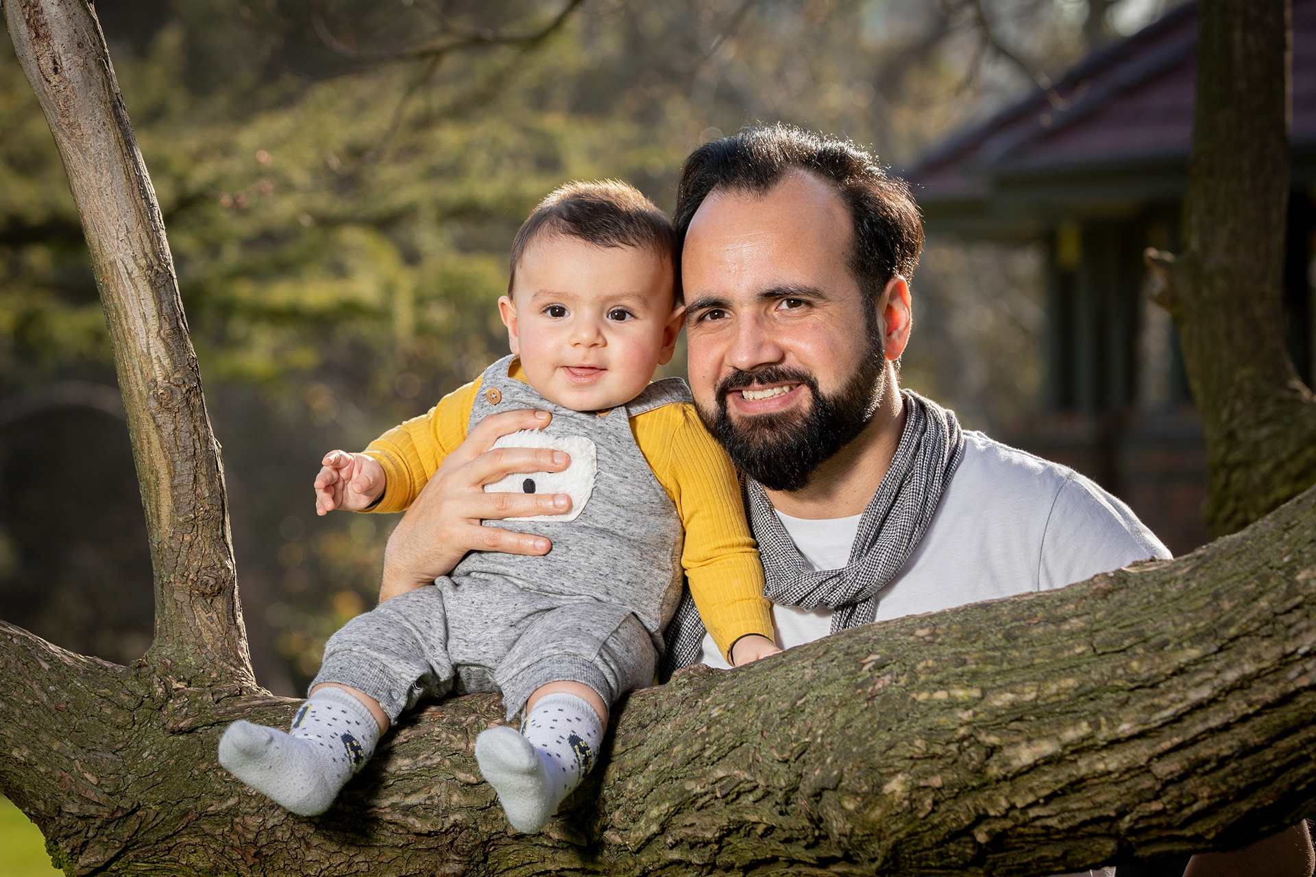 Two children sitting on a low tree branch