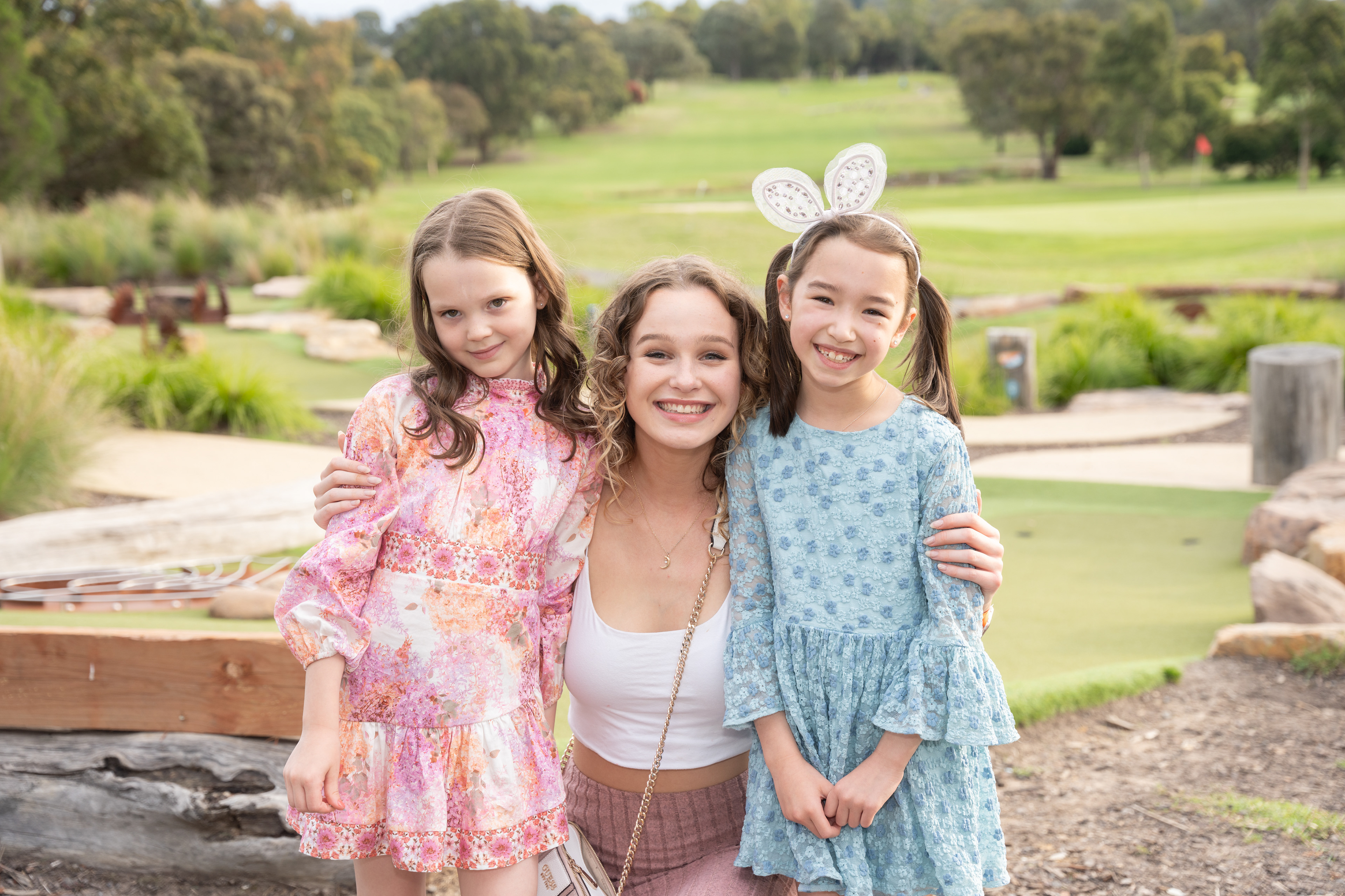 Three children posing together in a park