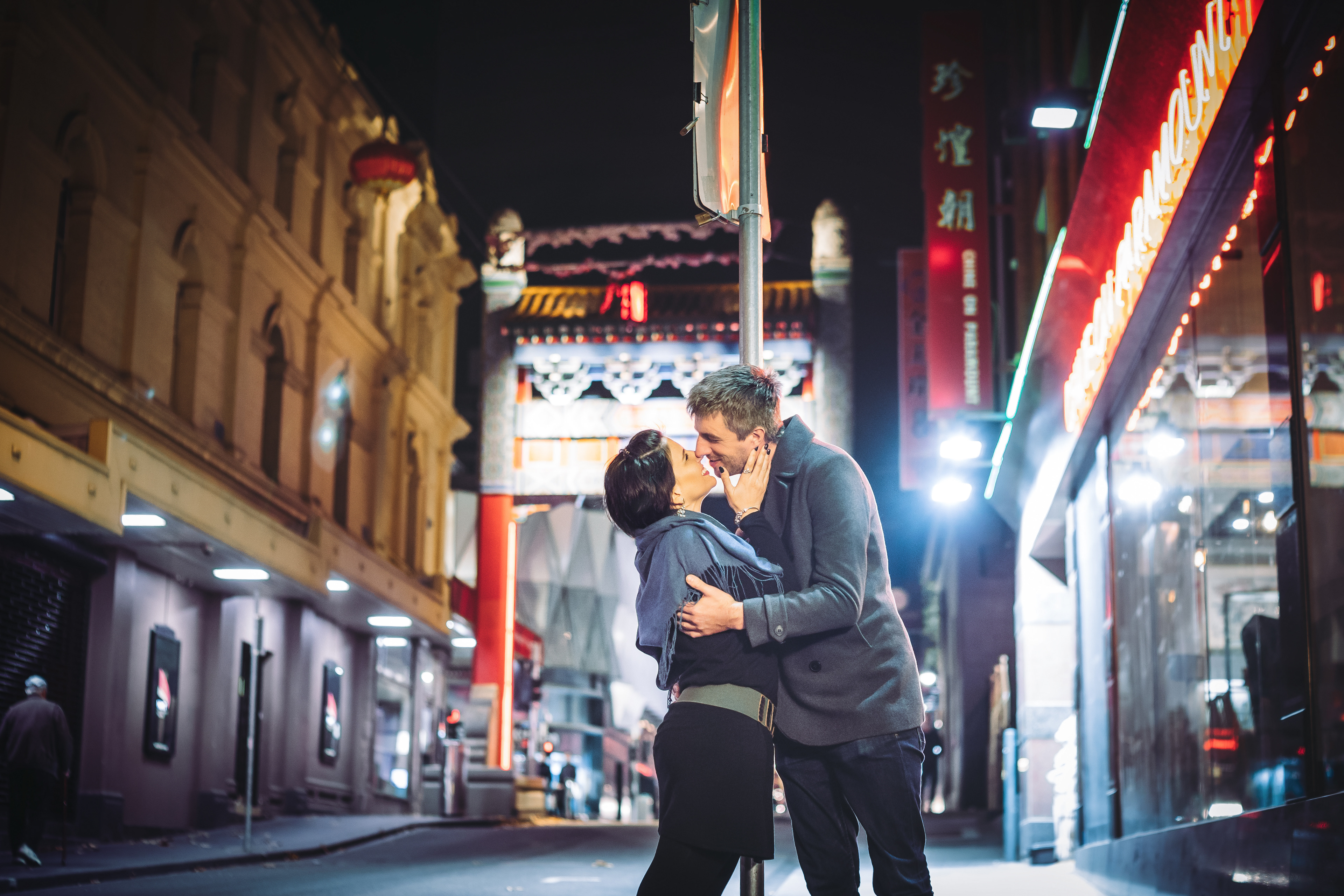 Couple posing on a brightly lit city street at night