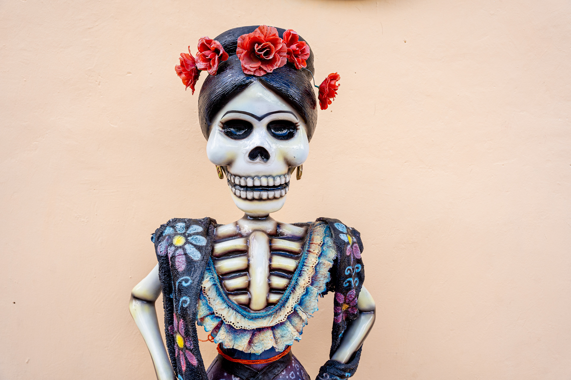 Portrait with skull face paint and red flowers