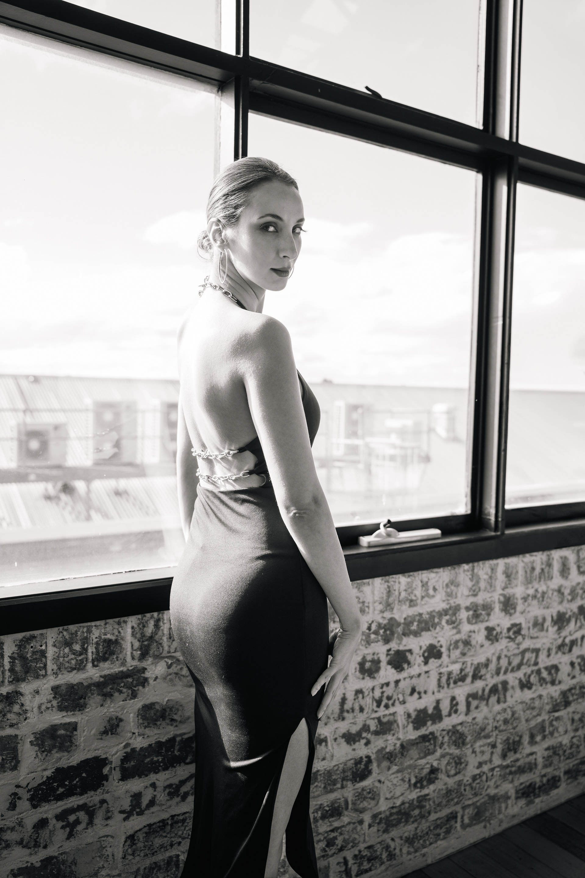 Black-and-white portrait beside a brick wall and window